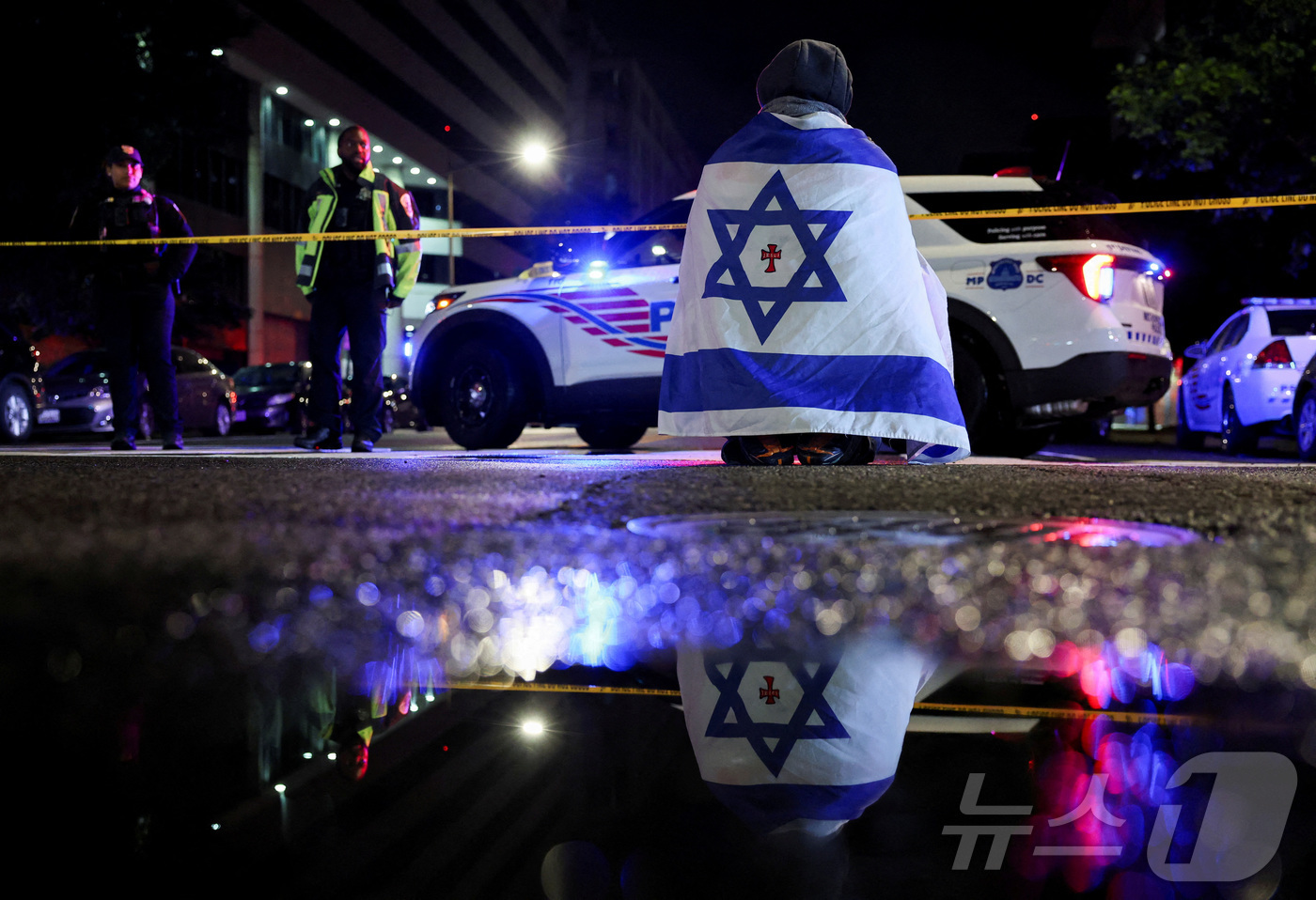 (워싱턴 DC 로이터=뉴스1) 신기림 기자 = 21일 미국 워싱턴 DC 유대인 박물관 근처에서 이스라엘 대사관 직원 2명이 총격을 받아 사망한 사건 현장에서 이스라엘 국기를 몸에 …