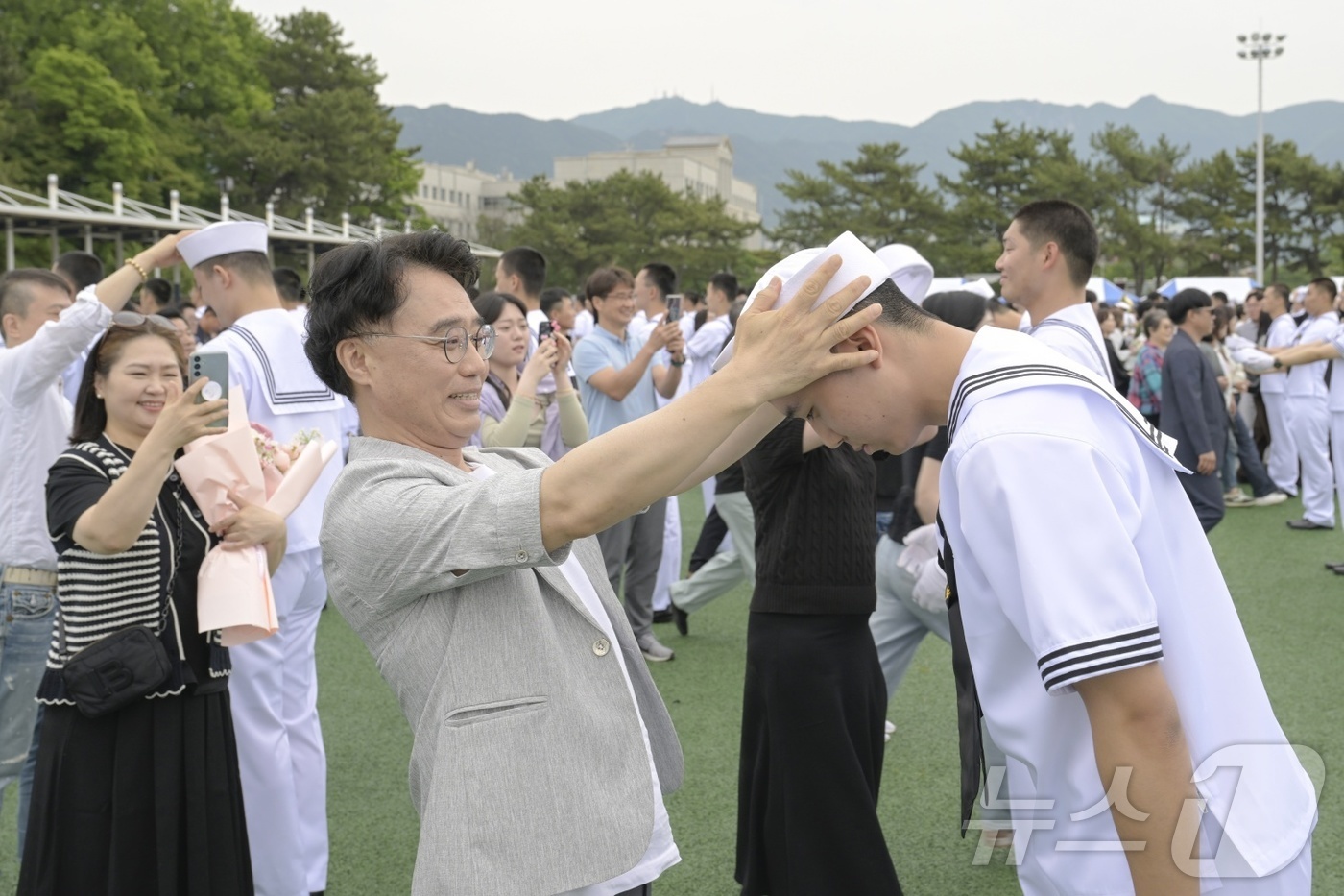(창원=뉴스1) 윤일지 기자 = 23일 경남 창원 진해구 해군교육사령부 기초군사교육단 연병장에서 열린 해군병 713기 수료식에서 가족이 해군병에게 정모를 씌워주고 있다. (해군교육 …