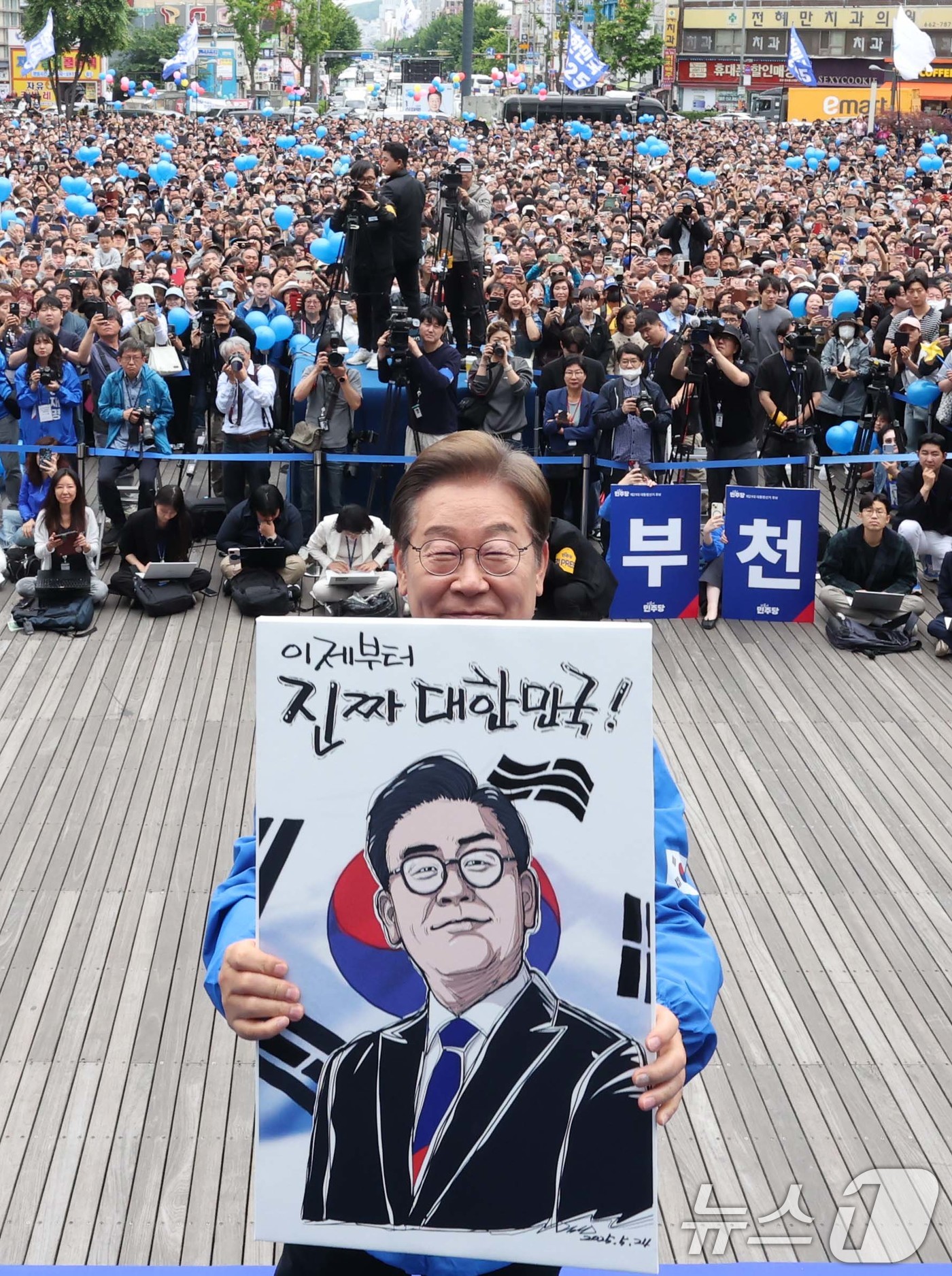 (부천=뉴스1) 이재명 기자 = 이재명 더불어민주당 대통령 후보가 24일 오후 경기도 부천시 부천역 북부광장에서 열린 유세에서 자신의 캐리커처 그림을 들어 보이고 있다. (공동취재 …