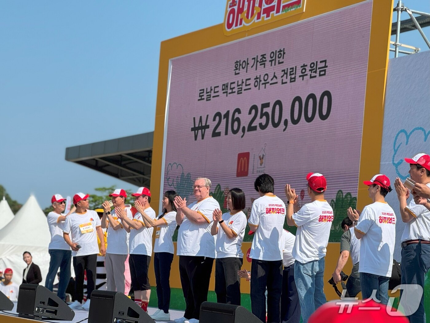 본문 이미지 - 오프닝 무대 화면에 행사 기부금 총액 2억 1625만 원을 공개하며 제프리 존스 RMHC 코리아 회장(가운데)을 비롯한 맥도날드 협력사 관계자들이 박수를 치고 있다.2025.5.25/뉴스1 ⓒ News1 이강 기자