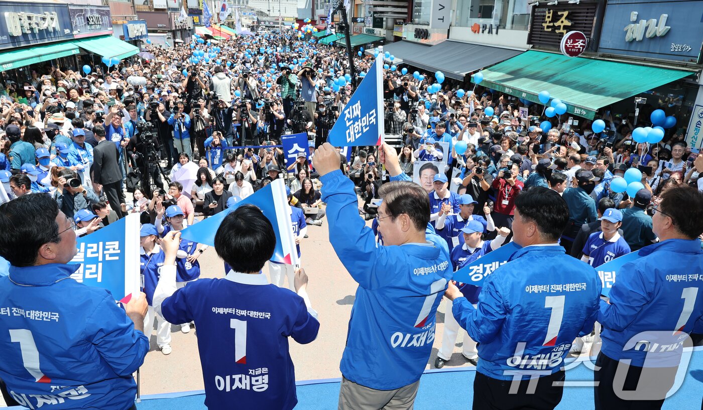 본문 이미지 - 이재명 더불어민주당 대통령 후보가 26일 오후 경기 수원시 팔달문 영동시장 입구를 찾아 &#39;진짜 대한민국&#39;이라고 적힌 깃발을 들고 있다. 2025.5.26/뉴스1 ⓒ News1 안은나 기자