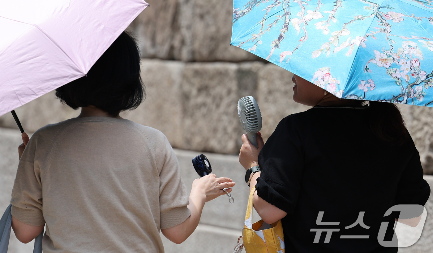 (서울=뉴스1) 신웅수 기자 = 26일 오후 서울 청계광장에서 시민들이 양산과 손 선풍기를 이용해 더위를 피하고 있다.기상청은 내일과 모레 동쪽 지방을 중심으로 요란한 소나기가 지 …