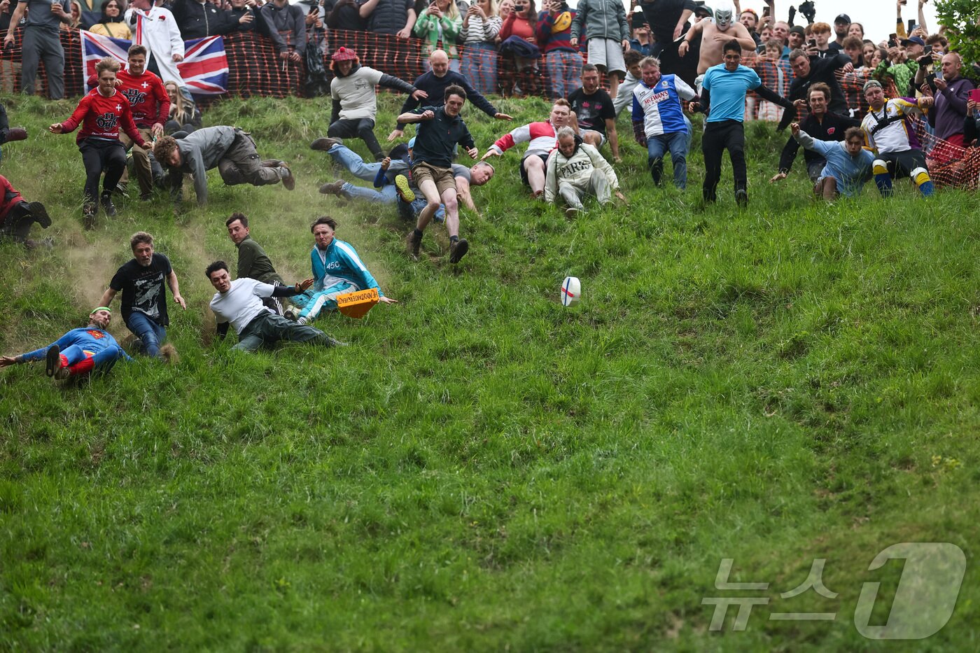본문 이미지 - 26일(현지시간) 영국 브록웍스의 쿠퍼스 힐에서 열린 '구르는 치즈 잡기' 대회에서 참가자들이 치즈를 쫒아 언덕을 내려가다 넘어지고 있다. ⓒ 로이터=뉴스1