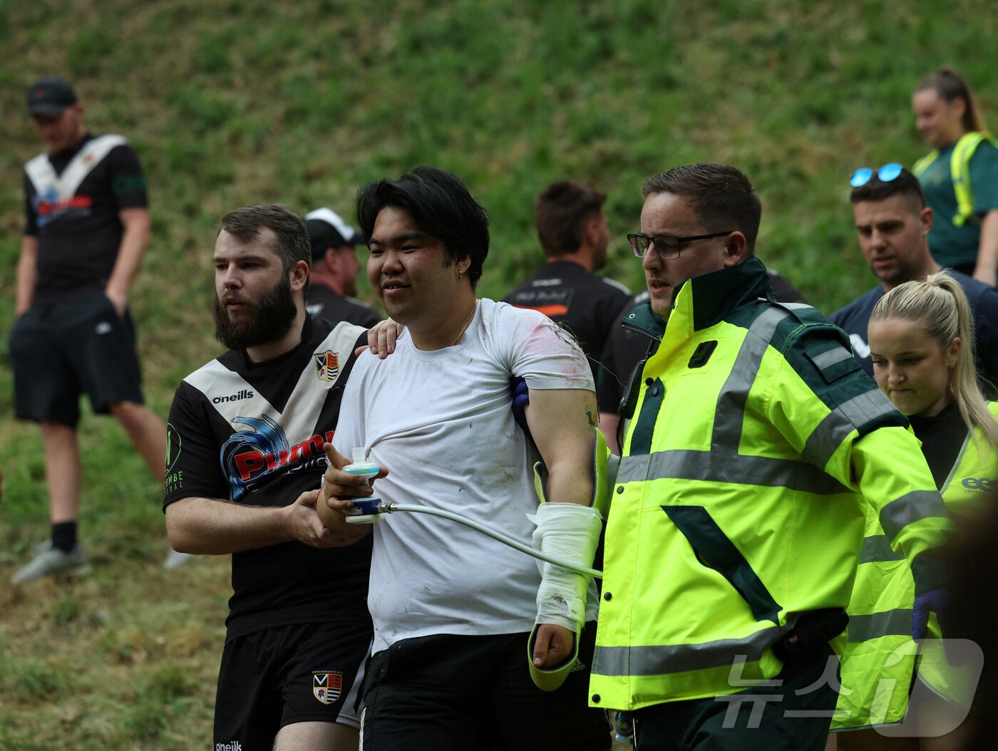 본문 이미지 - 26일(현지시간) 영국 브록웍스의 쿠퍼스 힐에서 열린 '구르는 치즈 잡기' 대회에서 한 참가자가 부상을 당해 호송되고 있다. ⓒ 로이터=뉴스1