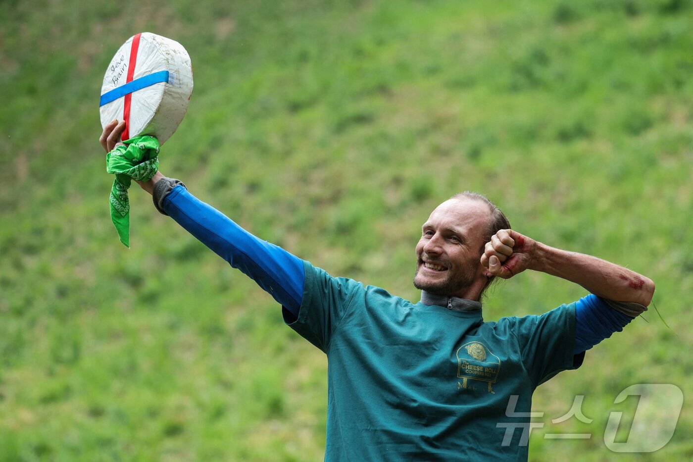 본문 이미지 - 26일(현지시간) 영국 브록웍스의 쿠퍼스 힐에서 열린 '구르는 치즈 잡기' 대회 두 번째 경기에서 우승한 루크 브릭스가 치즈 바퀴를 들고 포즈를 취하고 있다. ⓒ 로이터=뉴스1