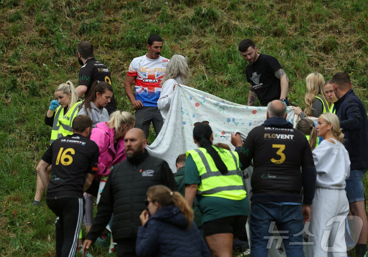 본문 이미지 - 26일(현지시간) 영국 브록웍스의 쿠퍼스 힐에서 열린 '구르는 치즈 잡기' 대회에서 부상당한 참가자가 치료를 받고 있다. ⓒ 로이터=뉴스1