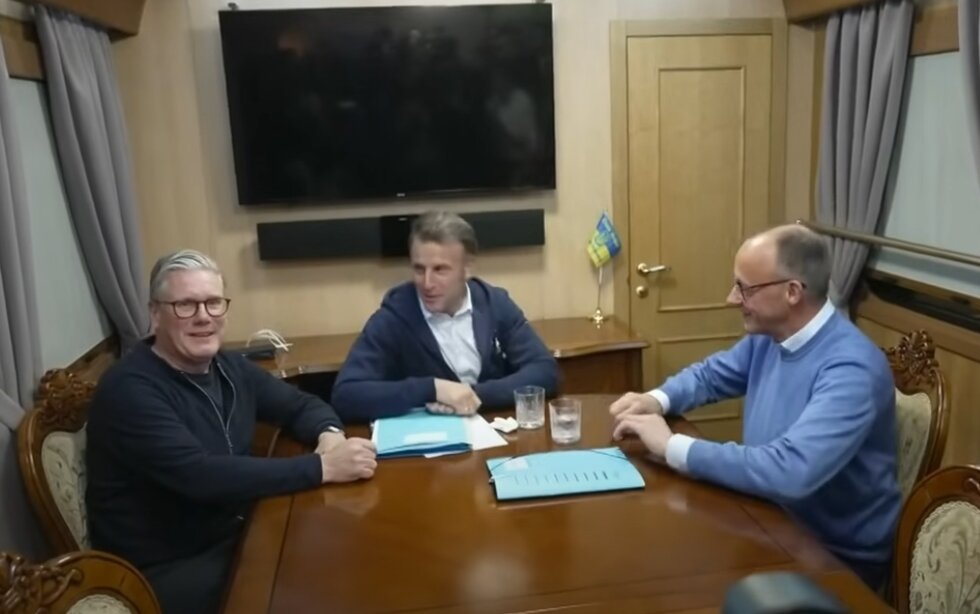 본문 이미지 - 에마뉘엘 마크롱 프랑스 대통령이 영국, 독일 정상들과의 기차 회담에서 테이블의 휴지를 치우려는 모습. 유튜브 화면 갈무리. 2025.05.13.