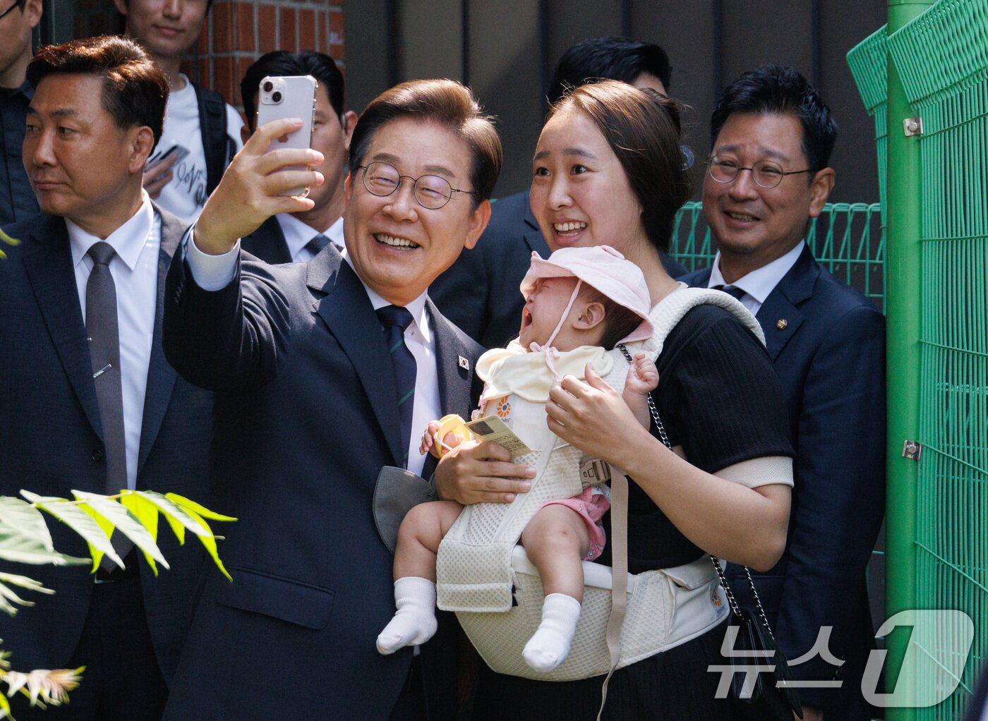 본문 이미지 - 이재명 더불어민주당 대통령 후보가 제21대 대통령선거 사전투표 첫날인 29일 오전 서울 서대문구 구 신촌동주민센터에서 청년들과 사전투표를 마친 뒤 아이를 안은 주민과 셀카를 찍고 있다. (공동취재) 2025.5.29/뉴스1 ⓒ News1 안은나 기자