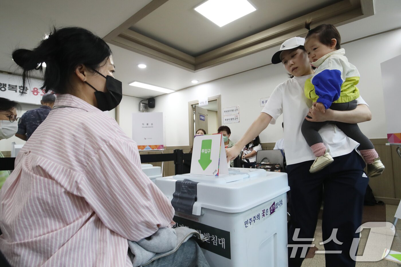 본문 이미지 - 제21대 대통령선거 사전투표 첫날인 29일 부산 남구 용호4동주민센터 마련된 사전투표소에서 유권자가 아이를 안고 투표하고 있다. 2025.5.29/뉴스1 ⓒ News1 윤일지 기자
