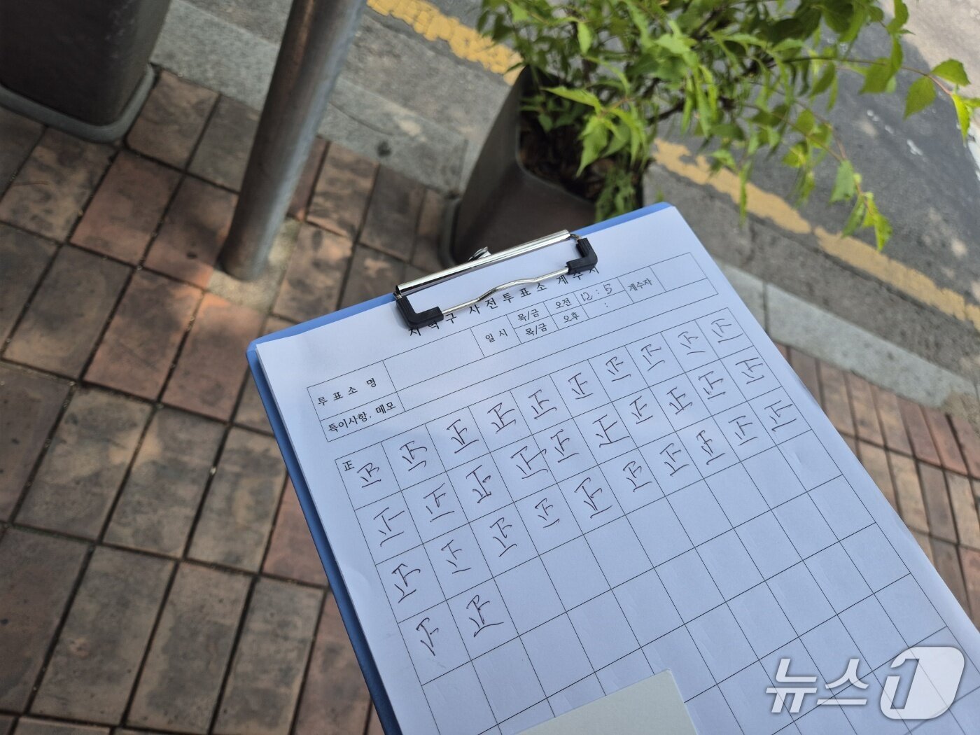 본문 이미지 -  21대 대통령 선거 사전투표 첫날인 29일 오후 경기 구리시 인찬동 사전투표소 앞에서 80대 남성 A 씨가 투표소를 오가는 인원을 바를 정(正)자로 기록한 종이./뉴스1 양희문 기자