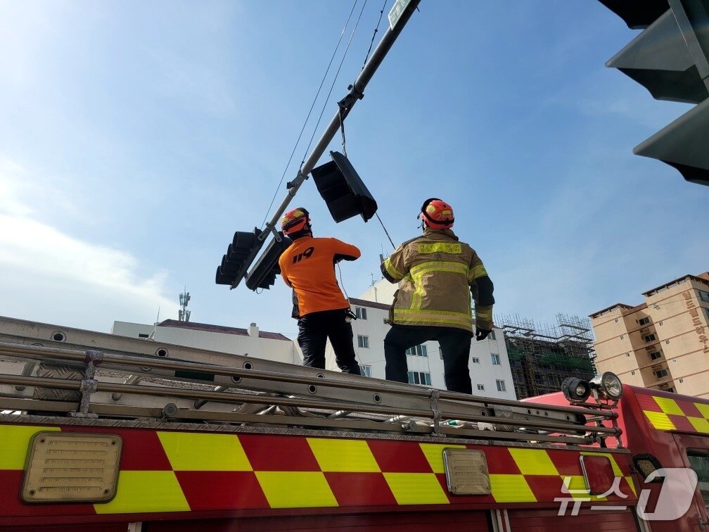 본문 이미지 - 3일 오전 9시30분쯤 제주시 애월읍의 한 도로에서 신호등 와이어가 강풍에 늘어져 신고를 받고 출동한 소방대원들이 안전조치를 하고 있다.(제주도소방안전본부 제공, 재판매 및 DB 금지)