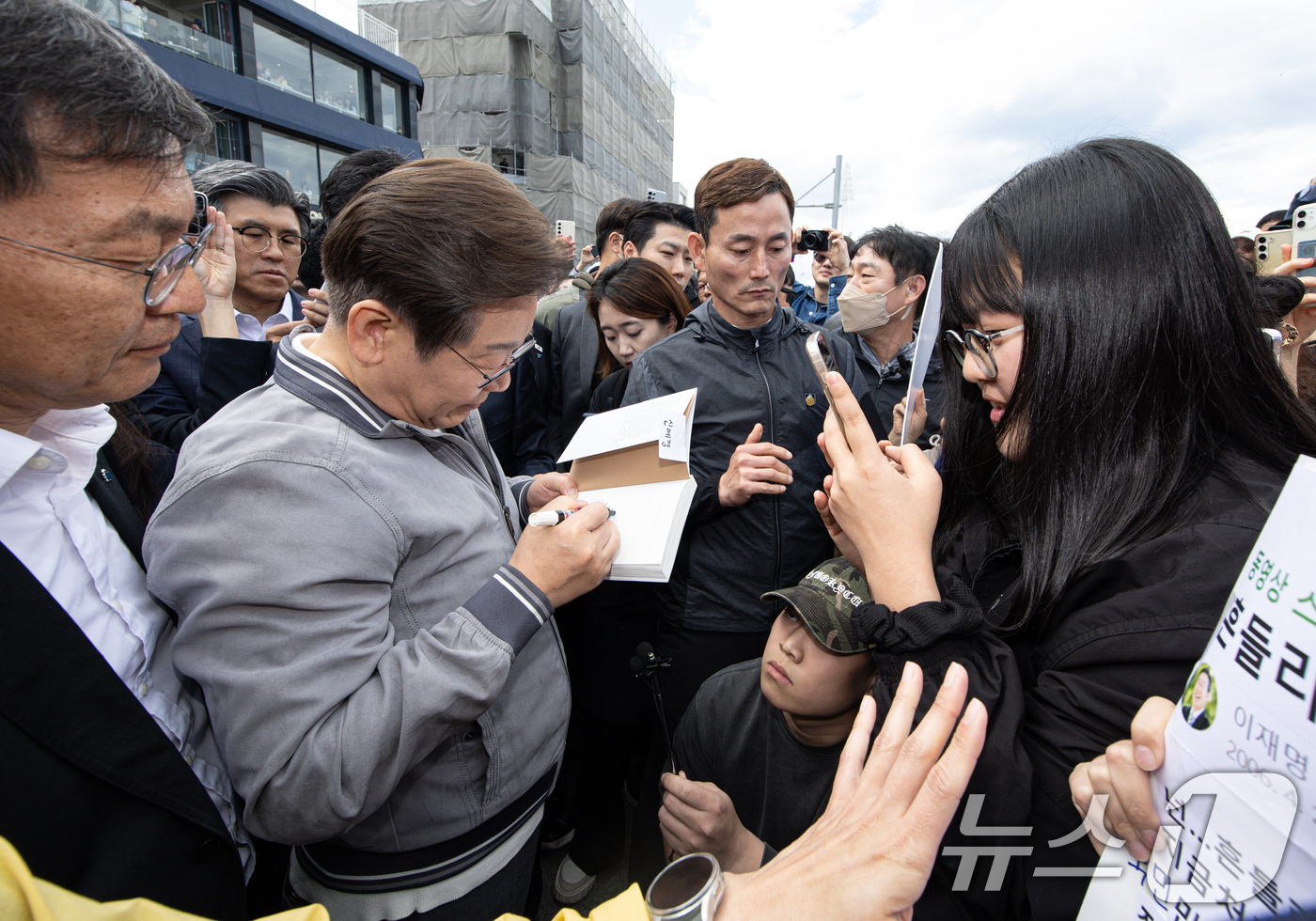 (강릉=뉴스1) 이재명 기자 = '골목골목 경청투어 : 동해안벨트편'에 나선 이재명 더불어민주당 대통령 후보가 3일 오후 강원 강릉시 안목해변에서 한 지지자 요청으로 책에 서명하고 …