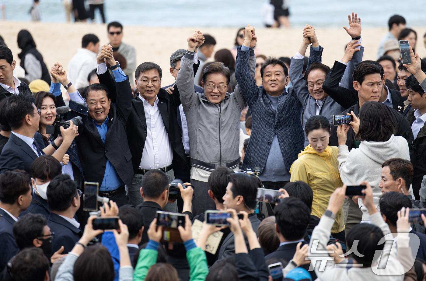 (강릉=뉴스1) 이재명 기자 = '골목골목 경청투어 : 동해안벨트편'에 나선 이재명 더불어민주당 대통령 후보가 3일 오후 강원 강릉시 안목해변에서 관계자들과 손을 들어보이고 있다. …