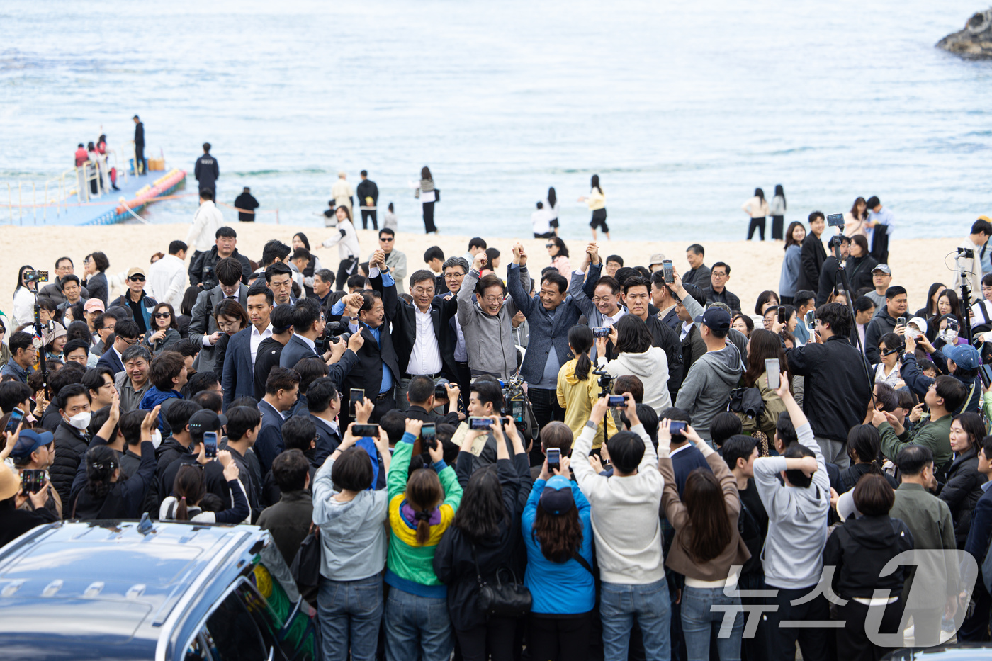 (강릉=뉴스1) 이재명 기자 = '골목골목 경청투어 : 동해안벨트편'에 나선 이재명 더불어민주당 대통령 후보가 3일 오후 강원 강릉시 안목해변에서 관계자들과 손을 들어보이고 있다. …