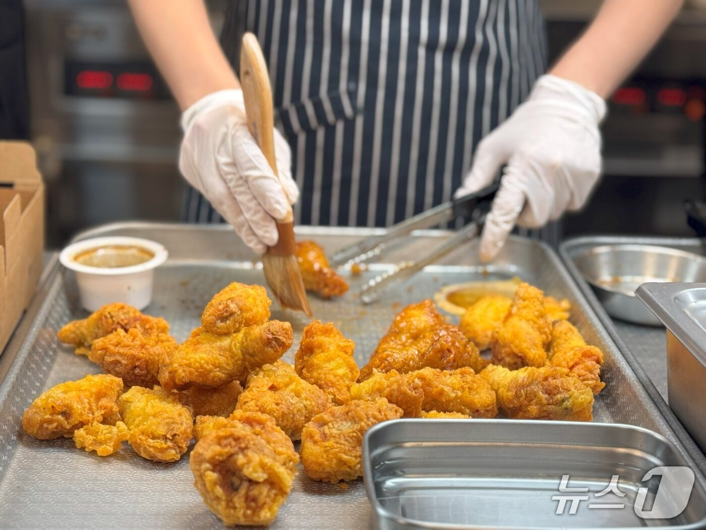 본문 이미지 - 30일 경기도 오산시에 위치한 교촌에프앤비의 R&D센터 '정구관'에서 '교촌 1991스쿨'프로그램을 진행한 가운데 박보라 아띠교육팀 담당이 허니콤보 소스 도포 과정을 시연하고 있다.2025.05.30/뉴스1 ⓒ News1 이강 기자