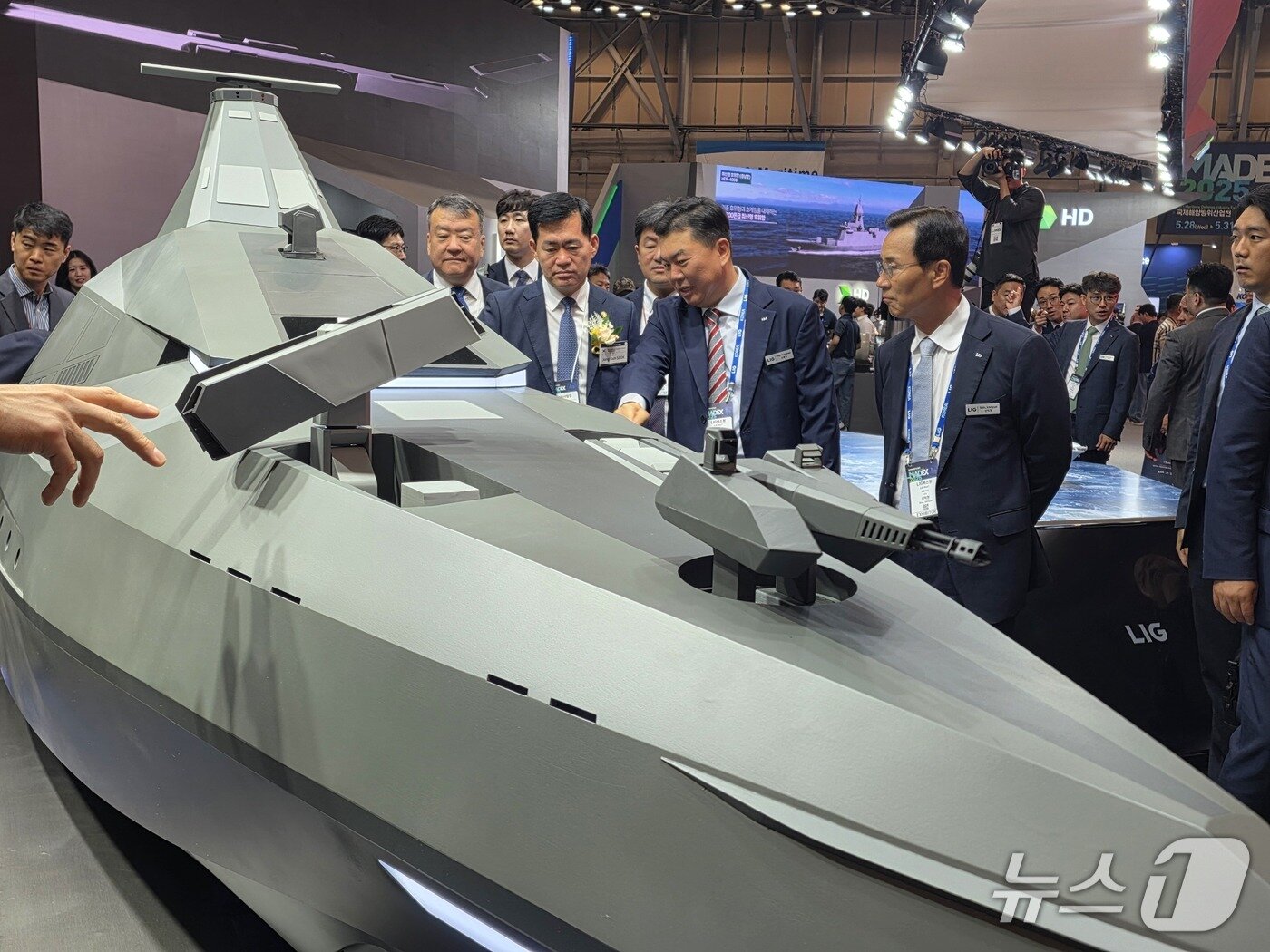본문 이미지 - 신익현 LIG넥스원 대표이사&#40;사진 오른쪽&#41;와 석종건 방위사업청장&#40;코사지 착용&#41;, 신용화 LIG넥스원 미래전장사업본부장이 28일 부산 벡스코에서 개막한 제14회 국제해양방위산업전&#40;MADEX·마덱스&#41;에서 전투용 무인수상정 &#39;해검-X&#39;를 둘러보고 있다&#40;LIG넥스원 제공&#41;. 2025.05.28.