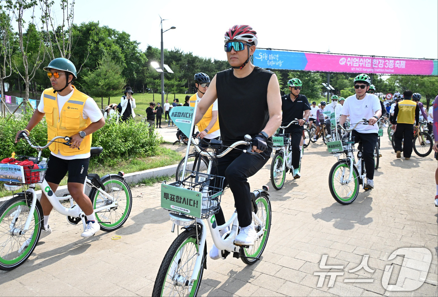 (서울=뉴스1) 오대일 기자 = 31일 제2회 쉬엄쉬엄 한강 3종 죽제 자전거 종목에 참가한 오세훈 서울시장이 '투표합시다' 깃발이 꽂힌 따릉이를 타고 한강 자전거도로를 달리고 있 …