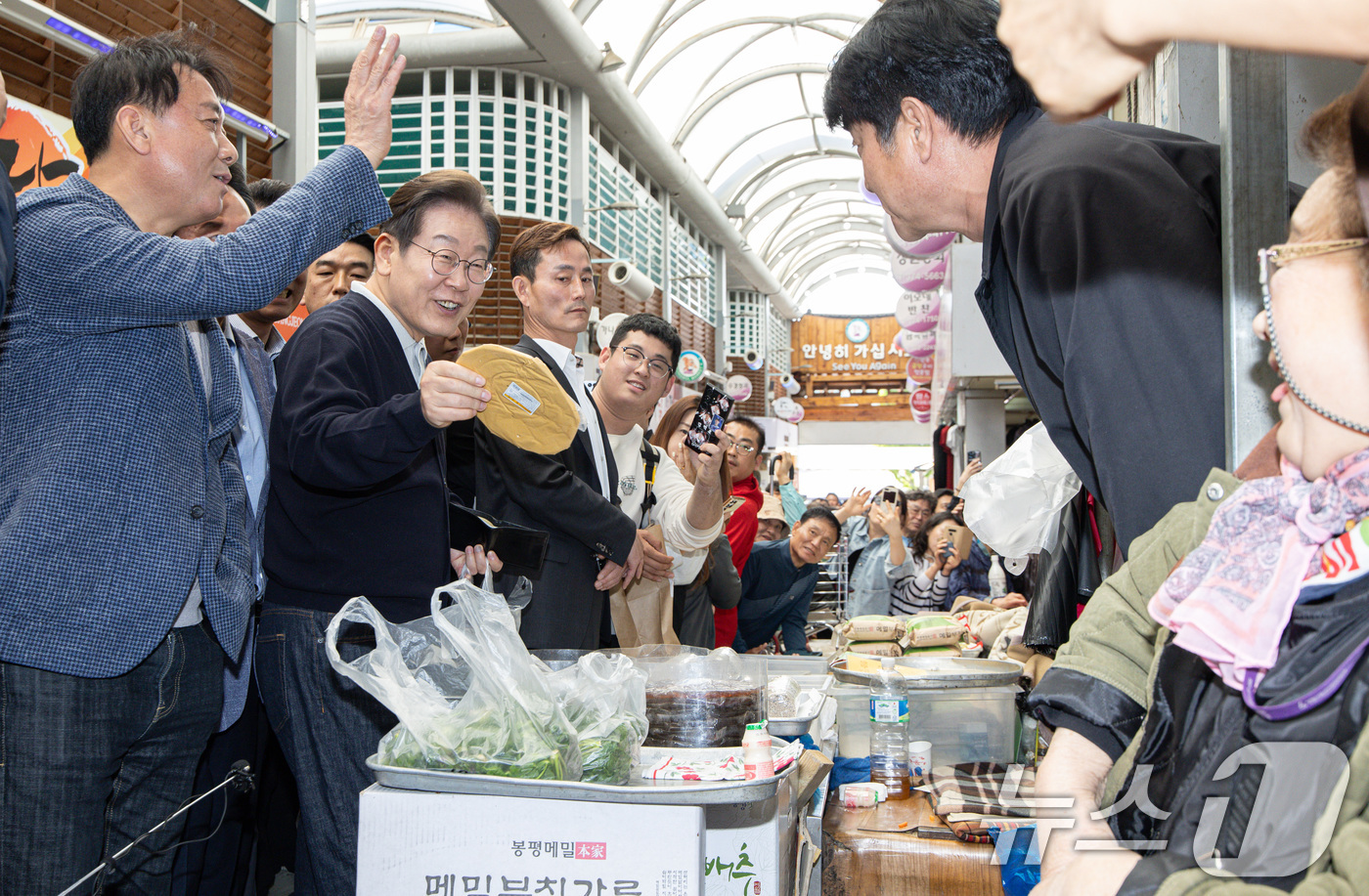 (영월=뉴스1) 이재명 기자 = '골목골목 경청투어 : 단양팔경편'에 나선 이재명 더불어민주당 대통령 후보가 4일 오후 강원 영월군 영월서부시장에서 호박엿을 구입하고 있다. 202 …