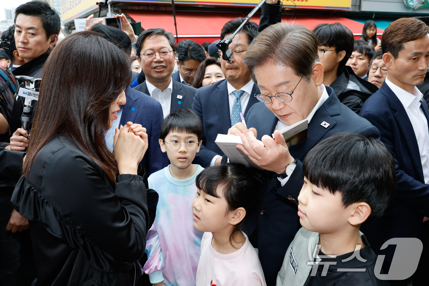 (양평=뉴스1) 안은나 기자 = 이재명 더불어민주당 대통령 후보가 2차 골목골목 경청투어에 나선 5일 오후 경기 양평군 양평시장의 문구점 앞에서 한 지지자에게 사인해주고 있다. 2 …