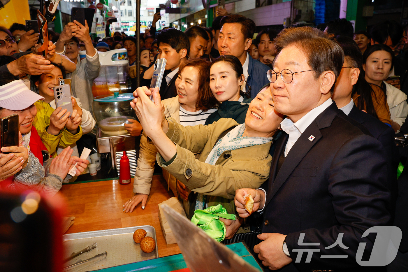 (음성=뉴스1) 안은나 기자 = 이재명 더불어민주당 대통령 후보가 2차 골목골목 경청투어에 나선 5일 오후 충북 음성군 무극시장을 찾아 시민과 셀카를 찍고 있다. 2025.5.5/ …