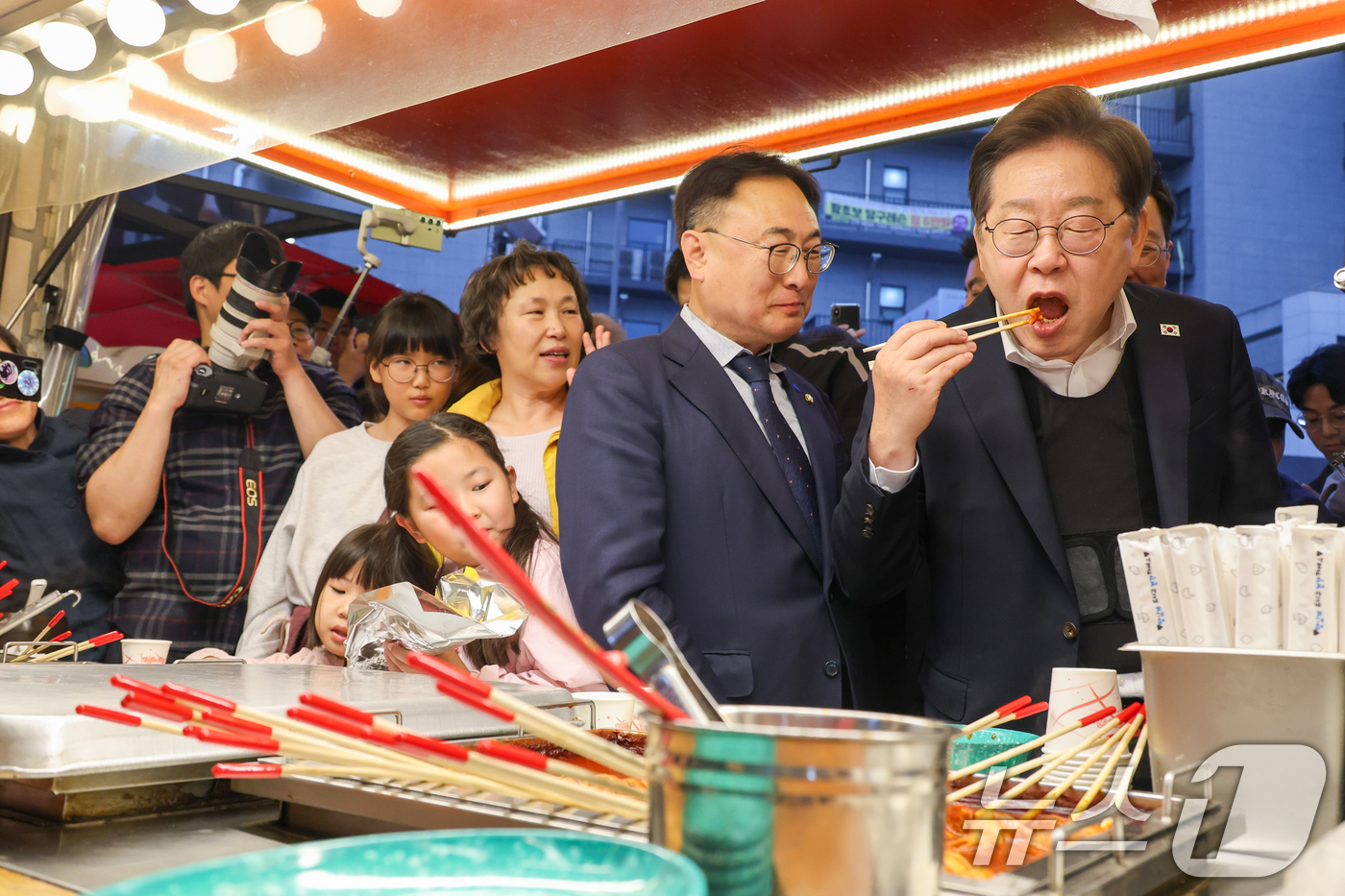 (진천=뉴스1) 안은나 기자 = 이재명 더불어민주당 대통령 후보가 2차 골목골목 경청투어에 나선 5일 오후 충북 진천군의 혁신도시 상가를 찾아 떡볶이를 먹고 있다. 2025.5.5 …