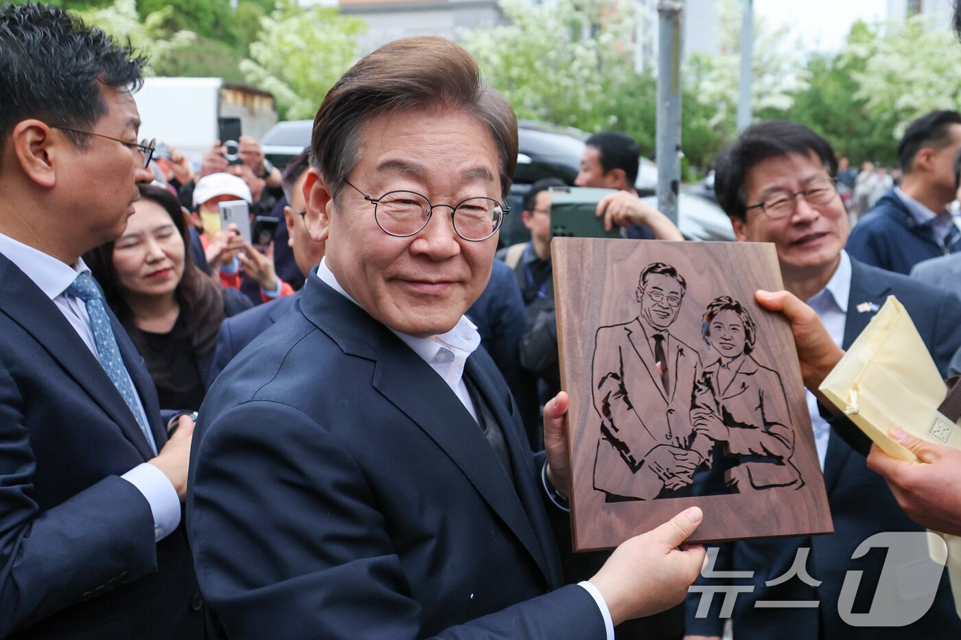 본문 이미지 - 이재명 더불어민주당 대통령 후보가 2차 골목골목 경청투어에 나선 5일 오후 충북 진천군의 혁신도시 상가를 찾아 한 시민으로부터 이 후보와 김혜경 여사를 나무판에 각인한 그림판을 선물받고 있다. 2025.5.5/뉴스1 ⓒ News1 안은나 기자