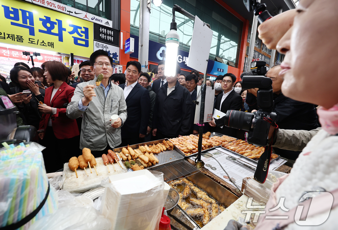 (포항=뉴스1) 김민지 기자 = 김문수 국민의힘 대통령 후보가 6일 경북 포항시 죽도시장에서 구매한 어묵을 먹으며 상인과 대화하고 있다. 2025.5.6/뉴스1