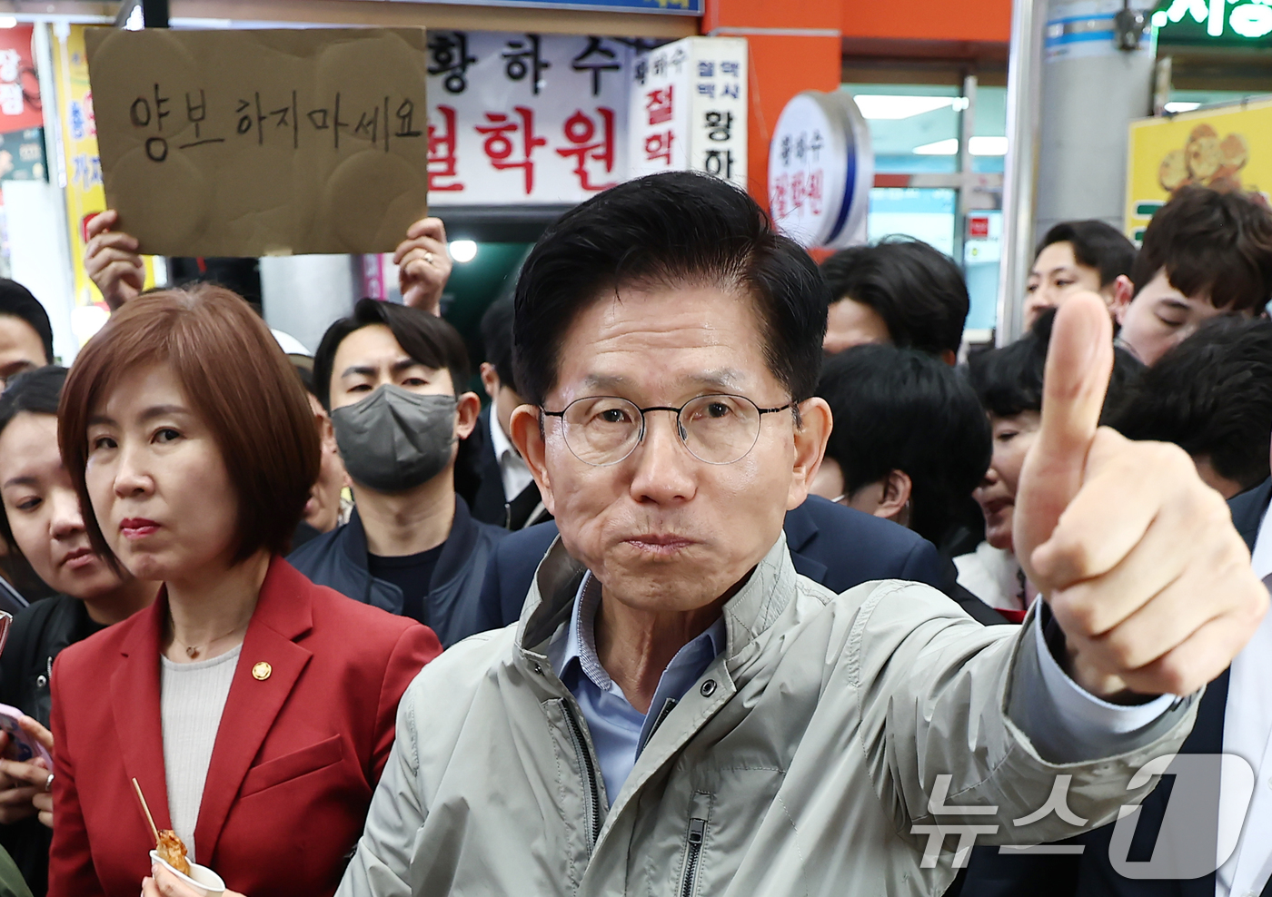 (포항=뉴스1) 김민지 기자 = 김문수 국민의힘 대통령 후보가 6일 경북 포항시 죽도시장에서 구매한 어묵을 먹으며 엄지를 치켜세우고 있다. 뒷편으로는 한 지지자가 '양보 하지 마세 …