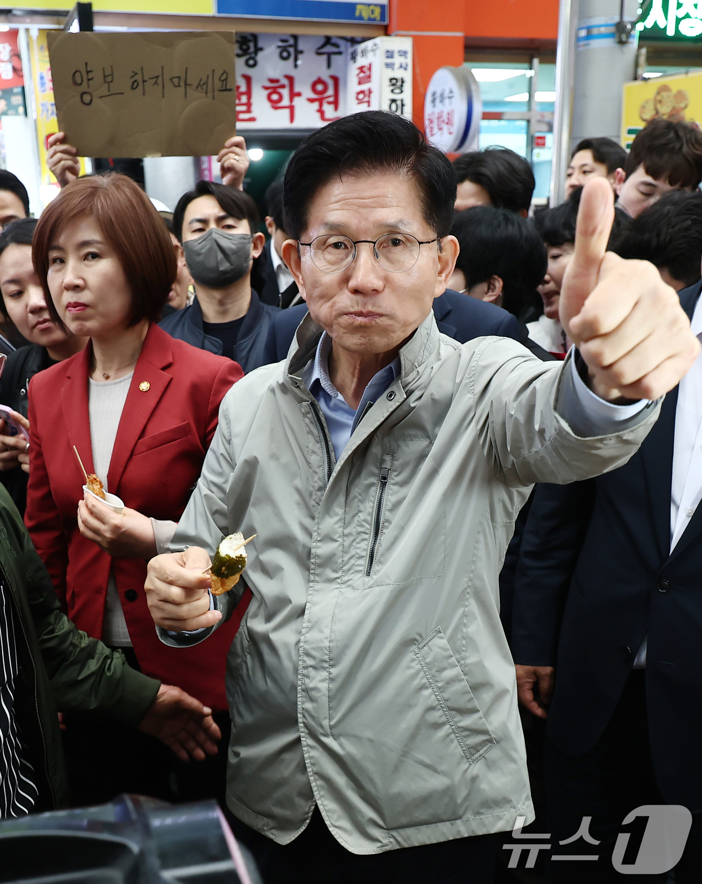 (포항=뉴스1) 김민지 기자 = 김문수 국민의힘 대통령 후보가 6일 경북 포항시 죽도시장에서 구매한 어묵을 먹으며 엄지를 치켜세우고 있다. 뒷편으로는 한 지지자가 '양보 하지 마세 …
