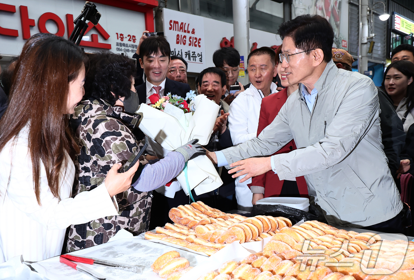 (포항=뉴스1) 김민지 기자 = 김문수 국민의힘 대통령 후보가 6일 경북 포항시 죽도시장에서 꽈배기를 구입하던 도중 상인에게 꽃다발을 건네고 있다. 2025.5.6/뉴스1