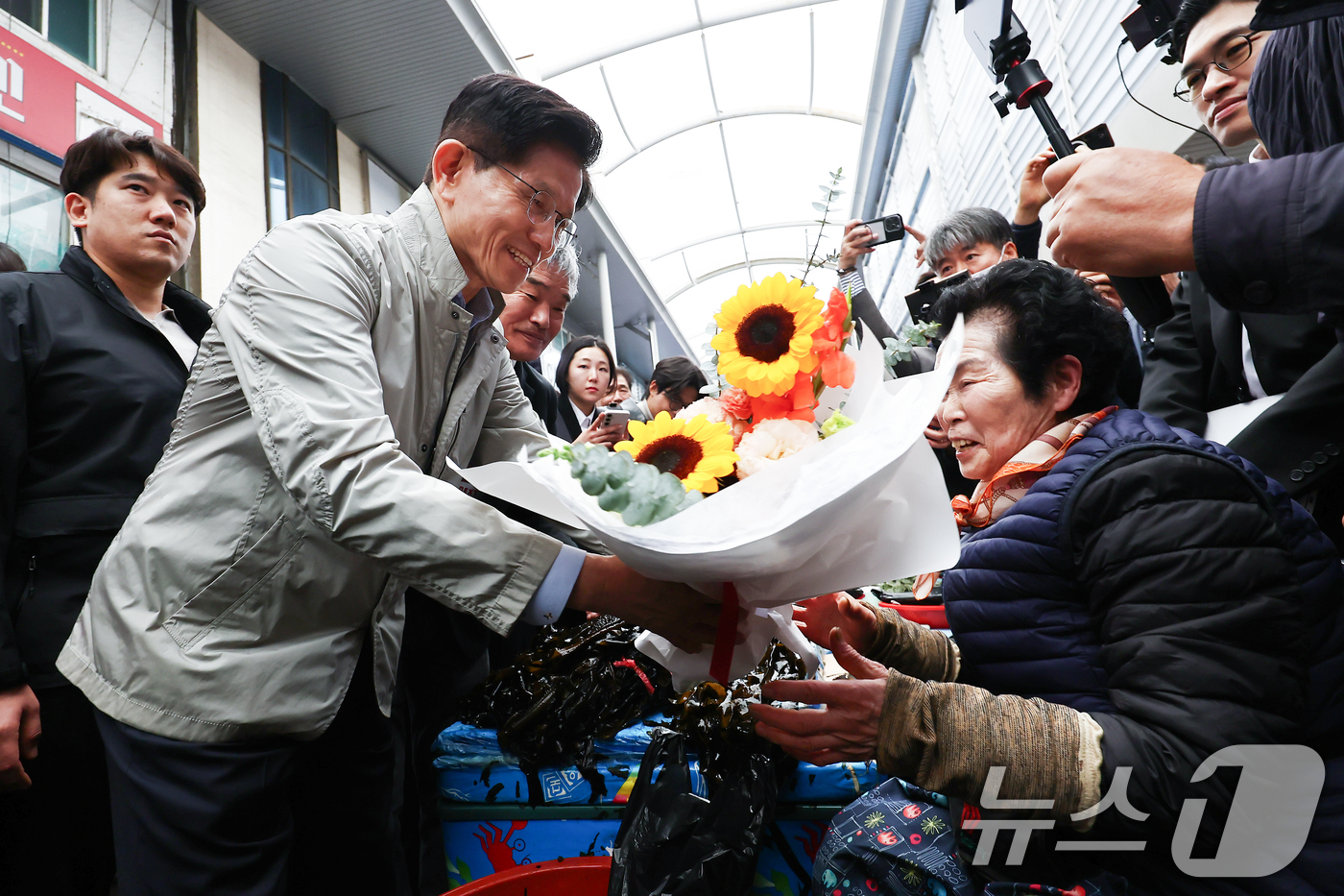 (포항=뉴스1) 김민지 기자 = 김문수 국민의힘 대통령 후보가 6일 경북 포항시 죽도시장에서 상인에게 꽃다발을 건네고 있다. 2025.5.6/뉴스1