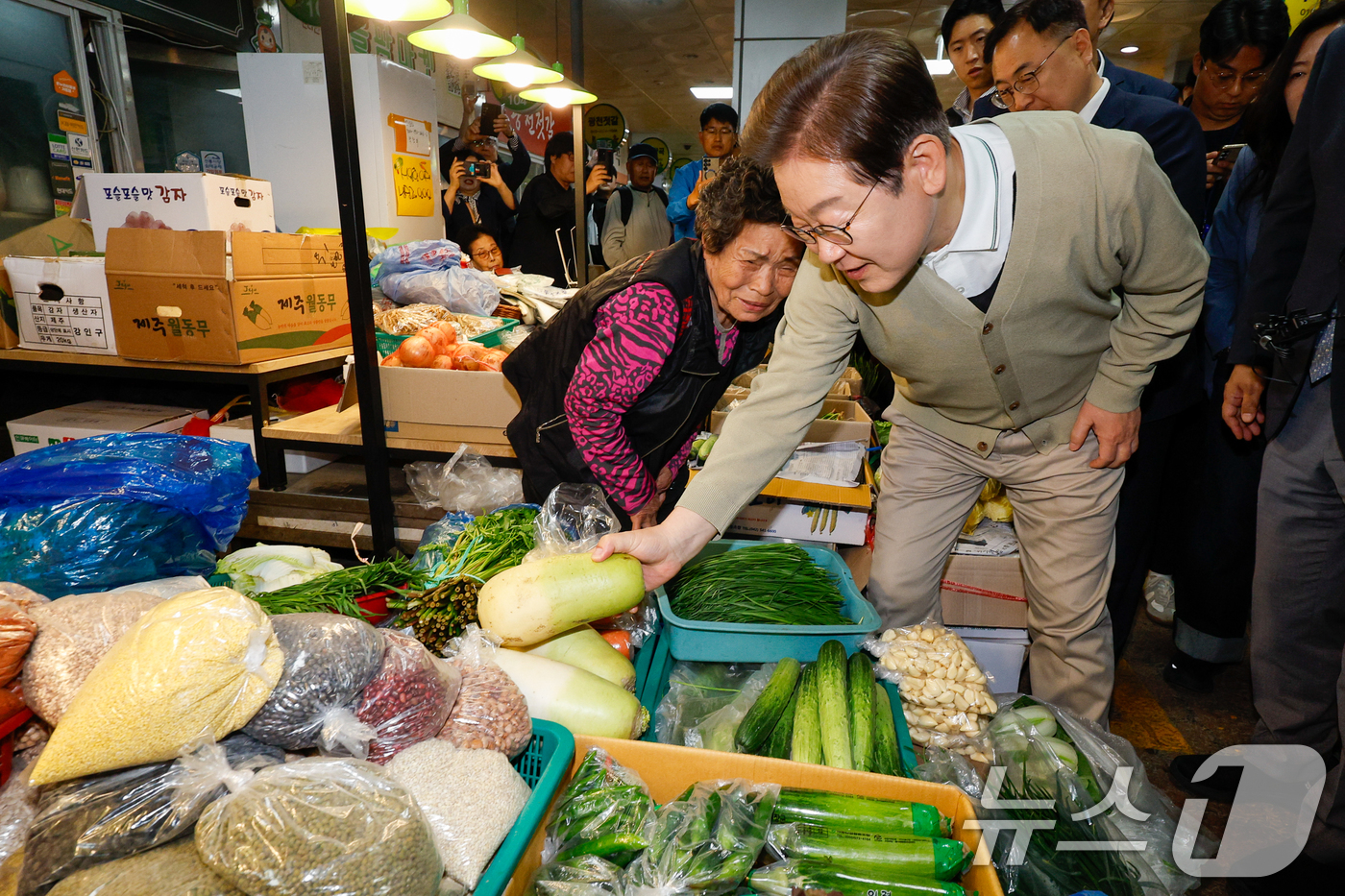 (옥천=뉴스1) 안은나 기자 = 이재명 더불어민주당 대통령 후보가 골목골목 경청투어 이틀차인 6일 오후 충북 옥천군 공설시장을 찾아 무를 구입하고 있다. 2025.5.6/뉴스1