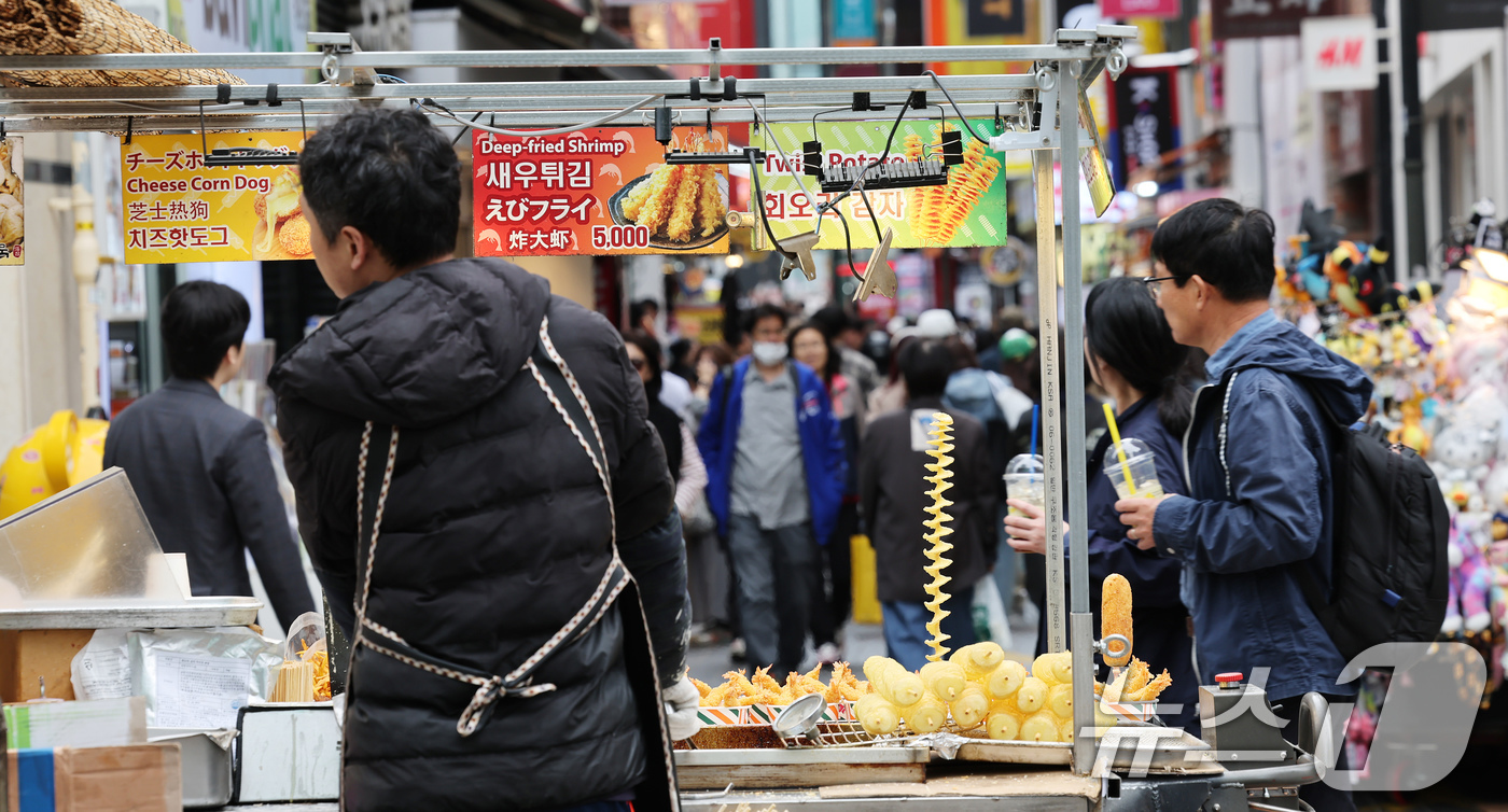 (서울=뉴스1) 장수영 기자 = 6일 서울 중구 명동거리를 찾은 관광객들이 거리에서 판매 중인 음식 앞으로 지나고 있다.통계청 소비자물가동향에 따르면 지난달 외식물가는 3.2% 상 …