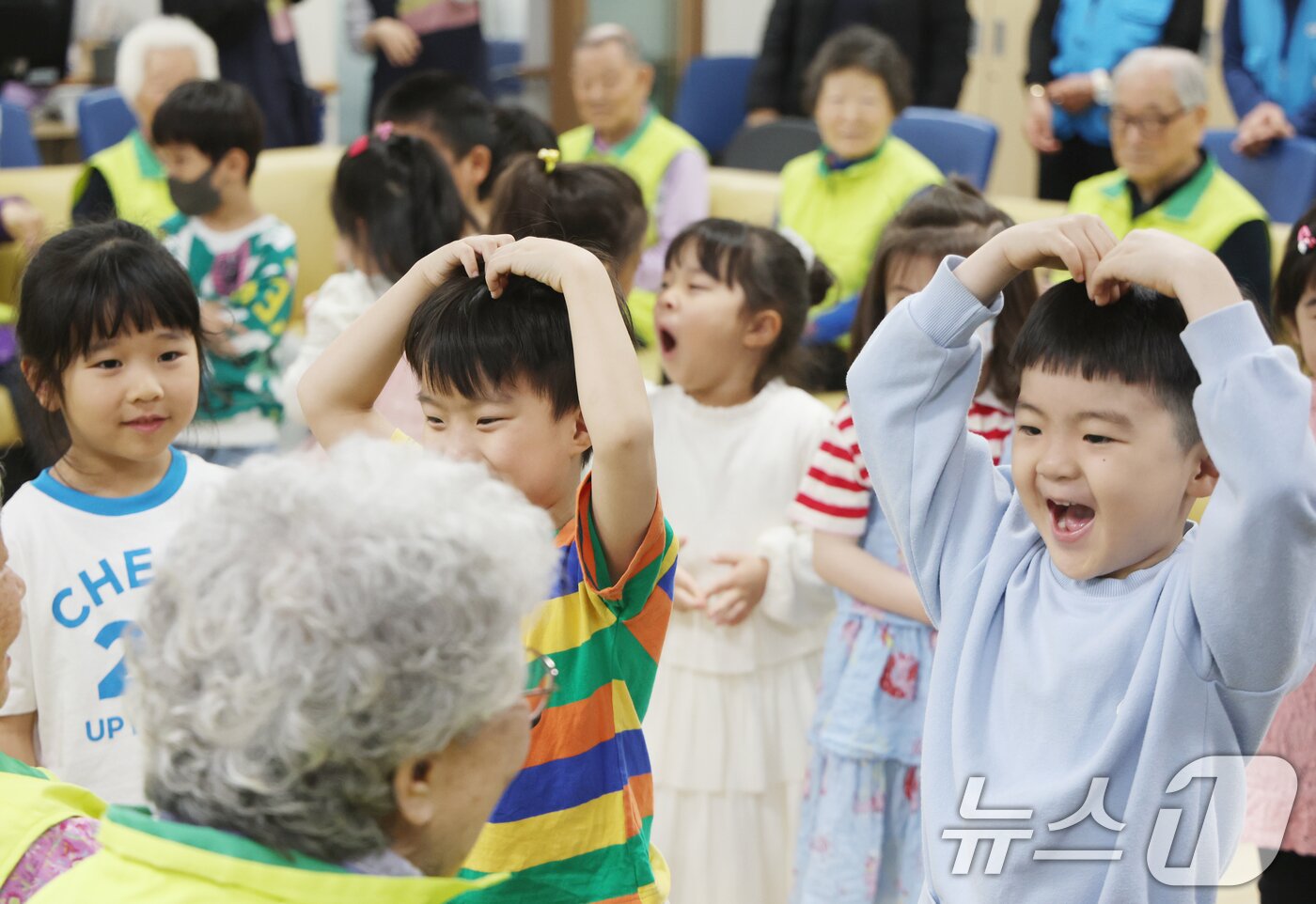 본문 이미지 - 어버이날을 하루 앞둔 7일 오전 경기 수원시 팔달구 팔달노인복지관에서 관내 어린이집 아이들이 어르신들에게 카네이션을 달아드리고 머리 위로 하트를 만들어보이고 있다. 2025.5.7/뉴스1 ⓒ News1 김영운 기자