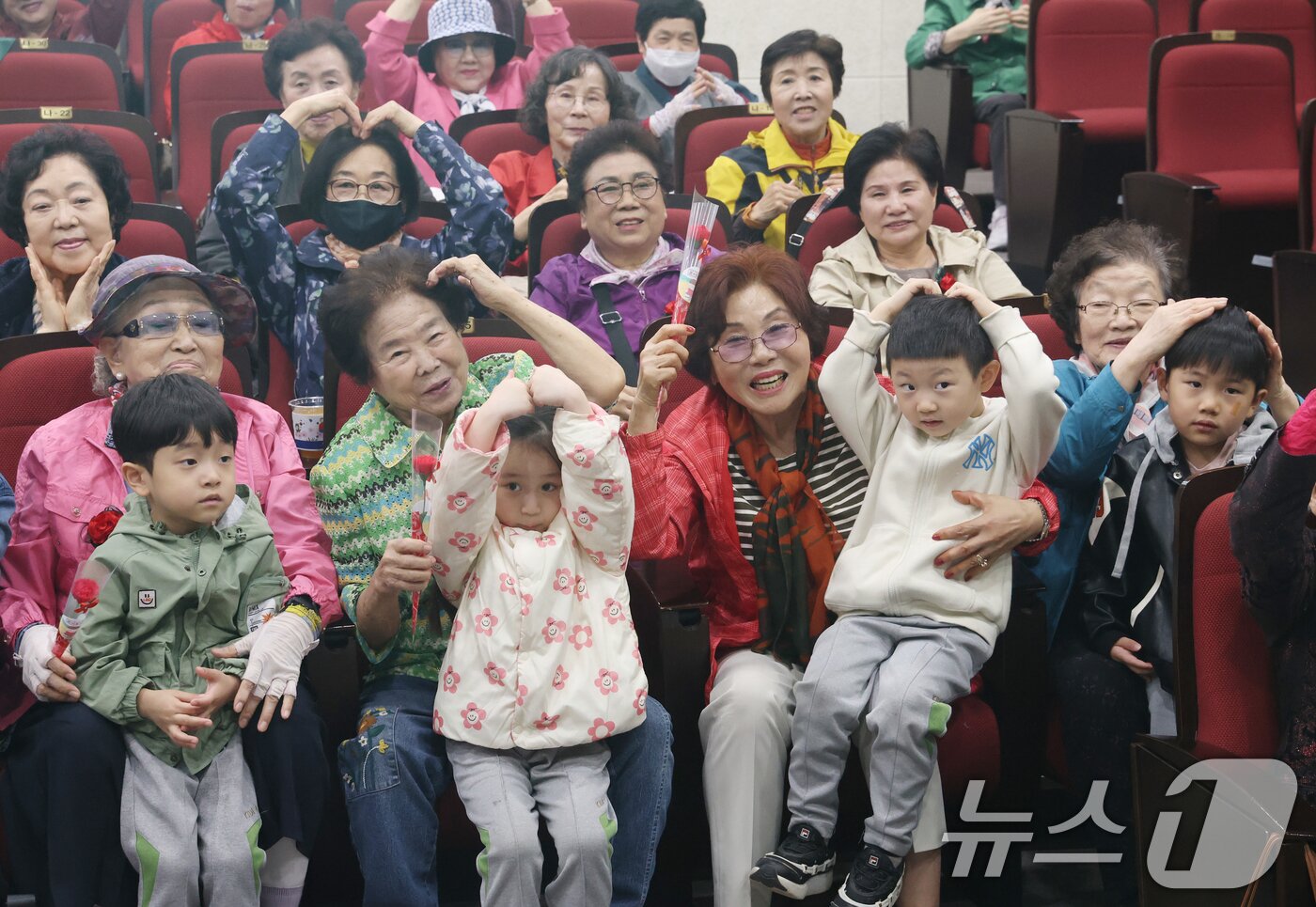 본문 이미지 - 어버이날을 하루 앞둔 7일 오전 경기 수원시 팔달구 팔달노인복지관에서 관내 어린이집 아이들이 어르신들에게 카네이션을 달아드리고 머리 위로 하트를 만들어보이고 있다. 2025.5.7/뉴스1 ⓒ News1 김영운 기자