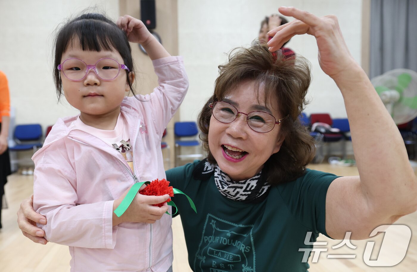 본문 이미지 - 어버이날을 하루 앞둔 7일 오전 경기 수원시 팔달구 팔달노인복지관에서 관내 어린이집 아이들이 어르신들에게 카네이션을 달아드리고 머리 위로 하트를 만들어보이고 있다. 2025.5.7/뉴스1 ⓒ News1 김영운 기자