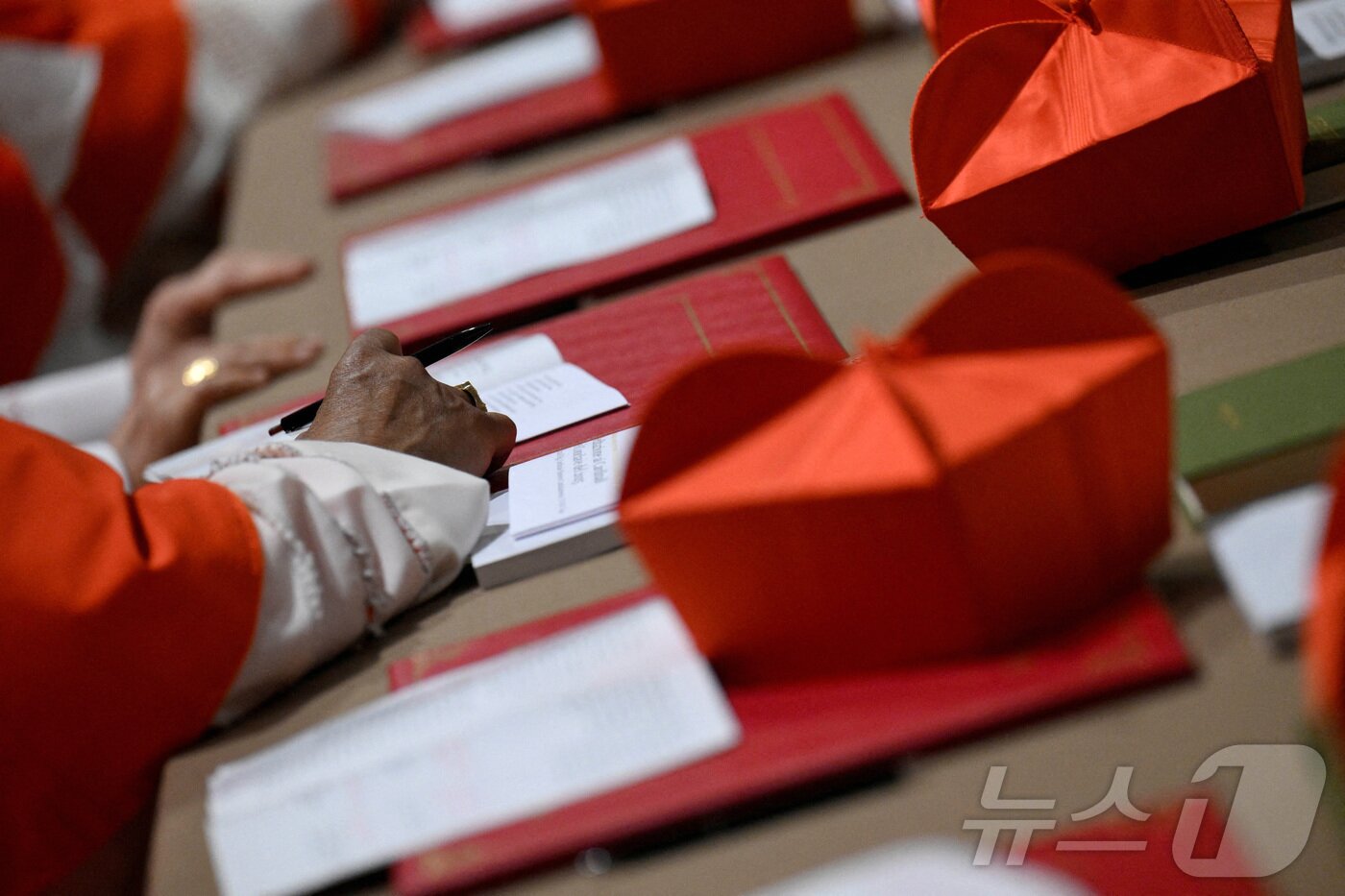 본문 이미지 - 새 교황을 선출하기 위한 콘클라베 첫날 7일&#40;현지시간&#41; 바티칸 시스티나 성당에서 추기경이 펜을 들고 있다. ⓒ 로이터=뉴스1