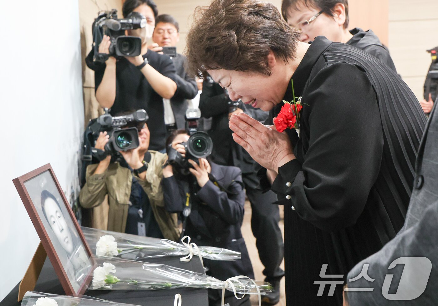 본문 이미지 - 8일 서울 동작구 국방부유해발굴감식단에서 열린 6·25전사자 유해 얼굴복원 유가족 초청행사에서 故 송영환 일병의 딸인 송재숙 씨가 영정에 카네이션을 놓고 있다. 국방부 유해발굴감식단은 어버이날을 맞아 고인의 딸인 송재숙 씨를 국유단으로 초청, 유해를 바탕으로 완성한 2D 표준 영정과 감사패를 전달했다. 송 씨는 본인이 3살 때 세상을 떠난 아버지를 찾기 위해 2020년 직접 국유단을 방문, 유전자 시료를 제공했다. 2025.5.8/뉴스1 ⓒ News1 허경 기자