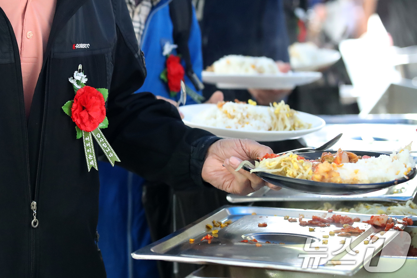 (대구=뉴스1) 공정식 기자 = 어버이날인 8일 오후 대구 달서구 두류공원 사랑해밥차 무료급식소에서 카네이션을 가슴에 단 어르신들이 줄지어 점심 배식을 받고 있다.무료급식소 측은 …