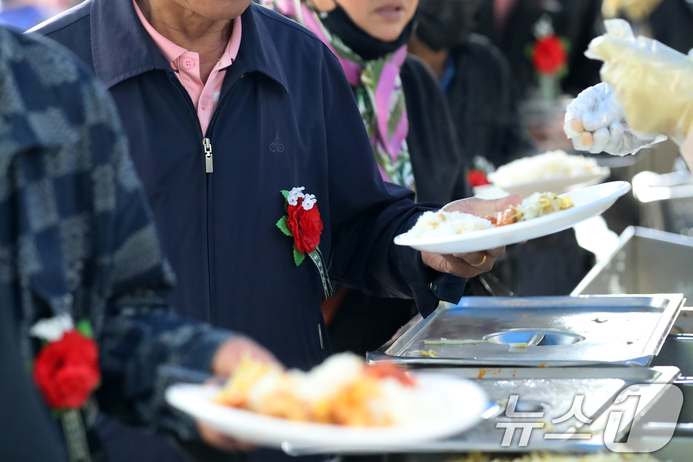 (대구=뉴스1) 공정식 기자 = 어버이날인 8일 오후 대구 달서구 두류공원 사랑해밥차 무료급식소에서 카네이션을 가슴에 단 어르신들이 줄지어 점심 배식을 받고 있다.무료급식소 측은 …