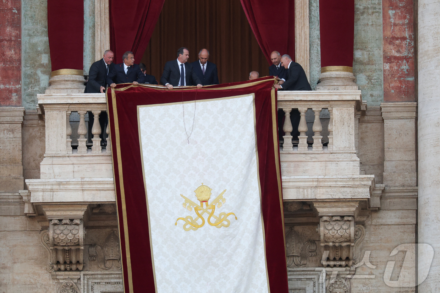 (로이터=뉴스1) = 8일(현지시간) 바티칸 성 베드로 대성당 로지아 발코니에 새 교황이 선출됐음을 알리는 대형 태피스트리가 걸리고 있다.ⓒ 로이터=뉴스1
