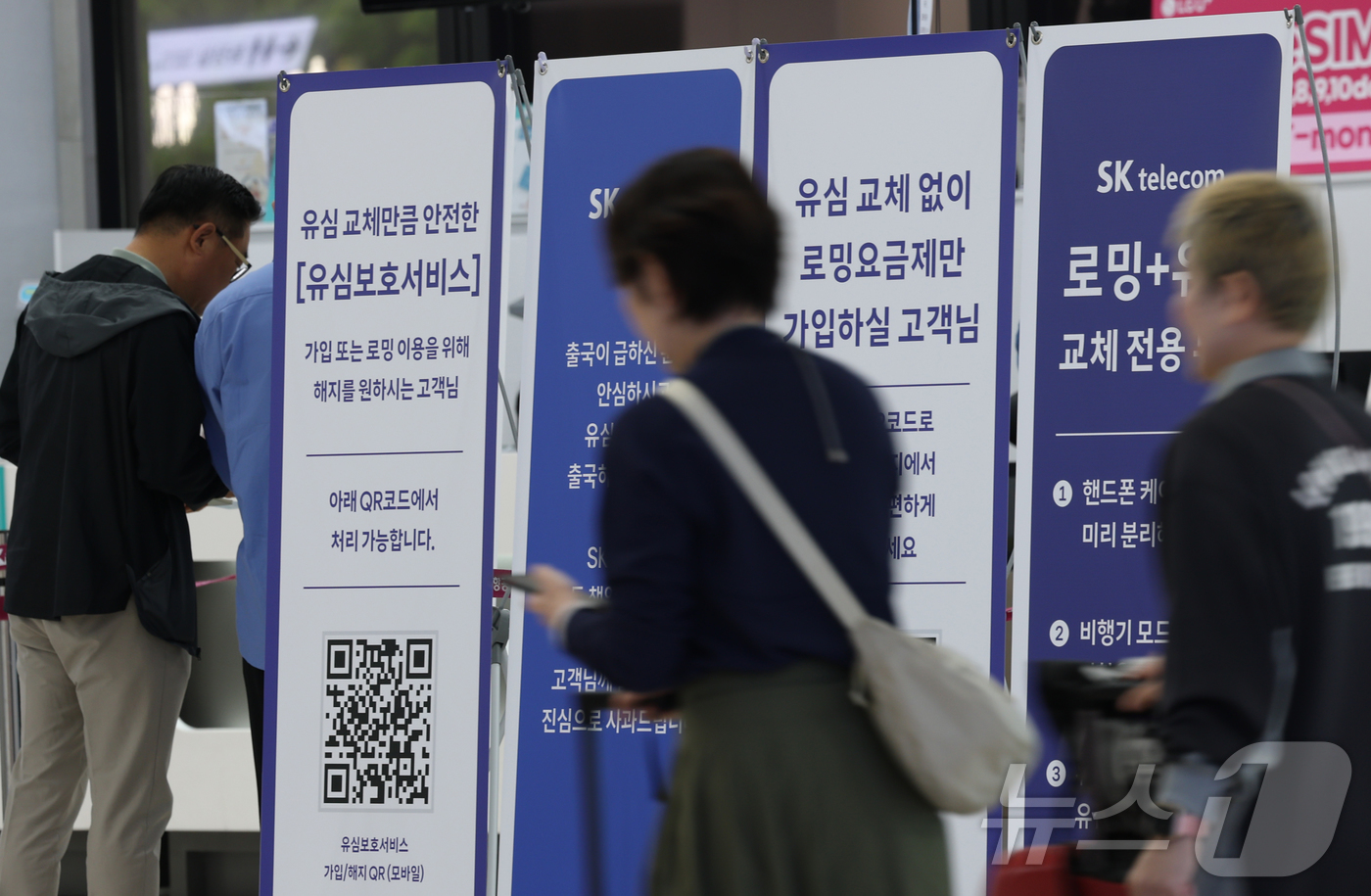 (김포공항=뉴스1) 권현진 기자 = 9일 김포국제공항 SK텔레콤(SKT) 로밍+유심 교체전용 부스앞에서 여행자들이 안내문을 살펴보고 있다.SKT는 9일까지 알뜰폰 포함 SKT 전체 …