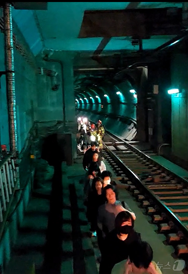 (서울=뉴스1) = 31일 오전 서울 지하철 5호선 마포역~여의나루역 구간을 지나는 열차에서 방화로 인한 화재가 발생, 승객들이 선로를 통해 대피하고 있다. (영등포소방서 제공. …