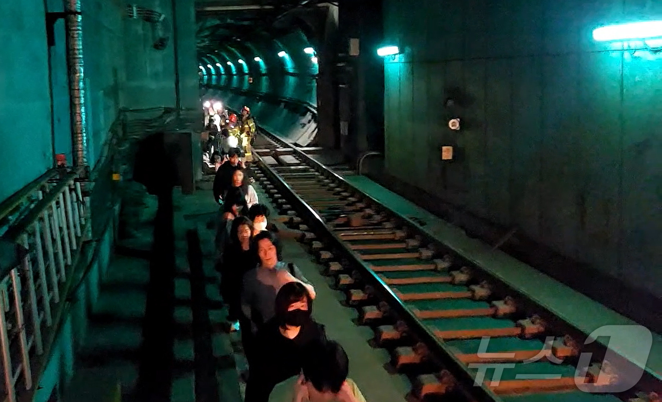 (서울=뉴스1) = 31일 오전 서울 지하철 5호선 마포역~여의나루역 구간을 지나는 열차에서 방화로 인한 화재가 발생, 승객들이 선로를 통해 대피하고 있다. (영등포소방서 제공. …