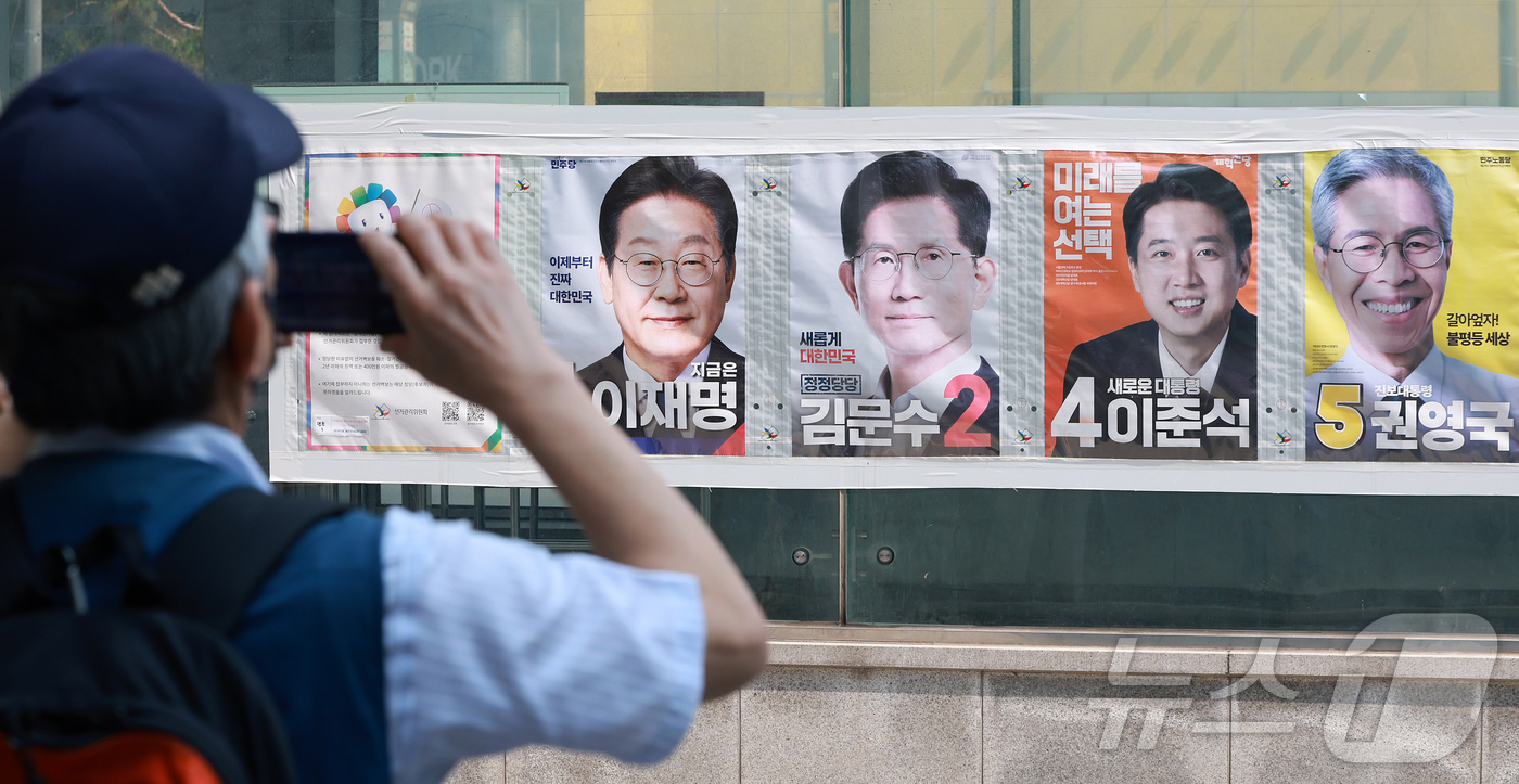 (서울=뉴스1) 김진환 기자 = 제21대 대통령선거가 이틀 앞으로 다가온 1일 서울 중구 4호선 명동역 앞에서 한 유권자가 후보자들의 선거 벽보를 스마트폰으로 촬영하고 있다. 20 …