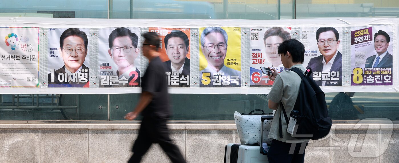 본문 이미지 - 제21대 대통령선거가 이틀 앞으로 다가온 1일 서울 중구 4호선 명동역 앞에서 시민들이 후보자들의 선거 벽보 앞으로 지나고 있다. 2025.6.1/뉴스1 ⓒ News1 김진환 기자