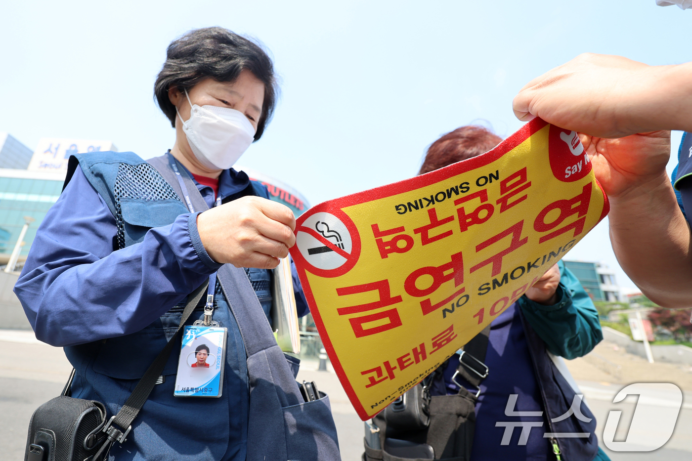 (서울=뉴스1) 황기선 기자 = 1일 오전 서울역광장에서 중구청 관계자들이 '금연구역' 안내 스티커를 붙이고 있다.이날부터 서울역광장과 인근 도로 약 5만 7천㎡가 금연구역으로 지 …
