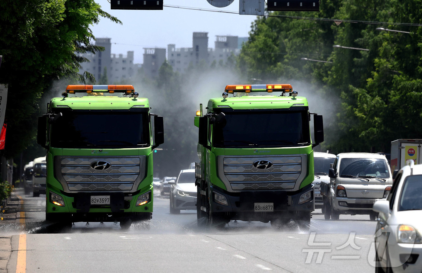 (광주=뉴스1) 박지현 기자 = 30도가 넘는 무더운 날씨가 이어지고 있는 11일 광주 북구청 기후환경과 기후변화대응팀 직원들이 살수차를 이용해 도로에 물을 뿌리고 있다. (광주 …