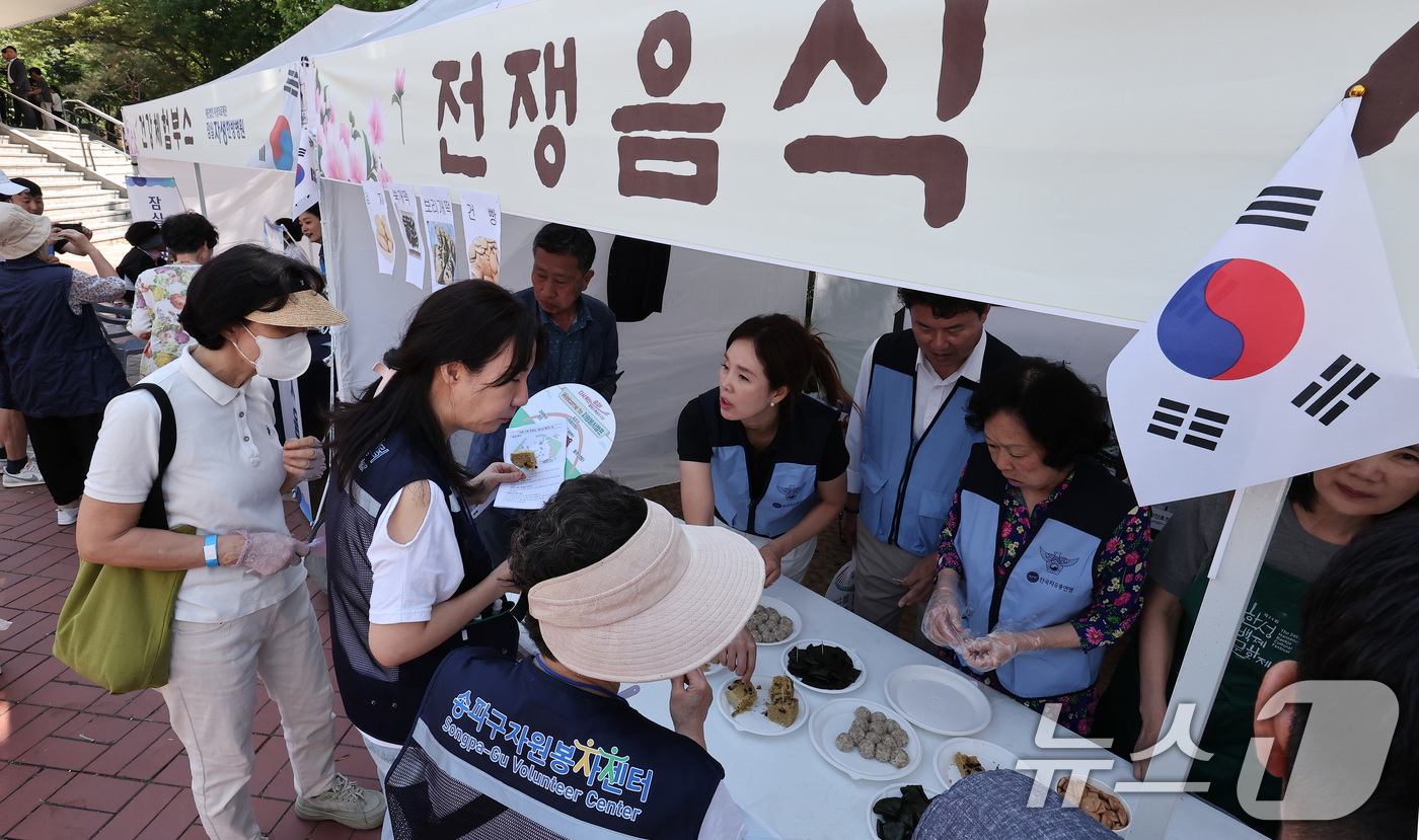 (서울=뉴스1) 김성진 기자 = 12일 서울 송파구 서울놀이마당에서 열린 '송파구 보훈가족 한마당 행사'에서 시민들이 전쟁음식 시식을 하고 있다. 2025.6.12/뉴스1