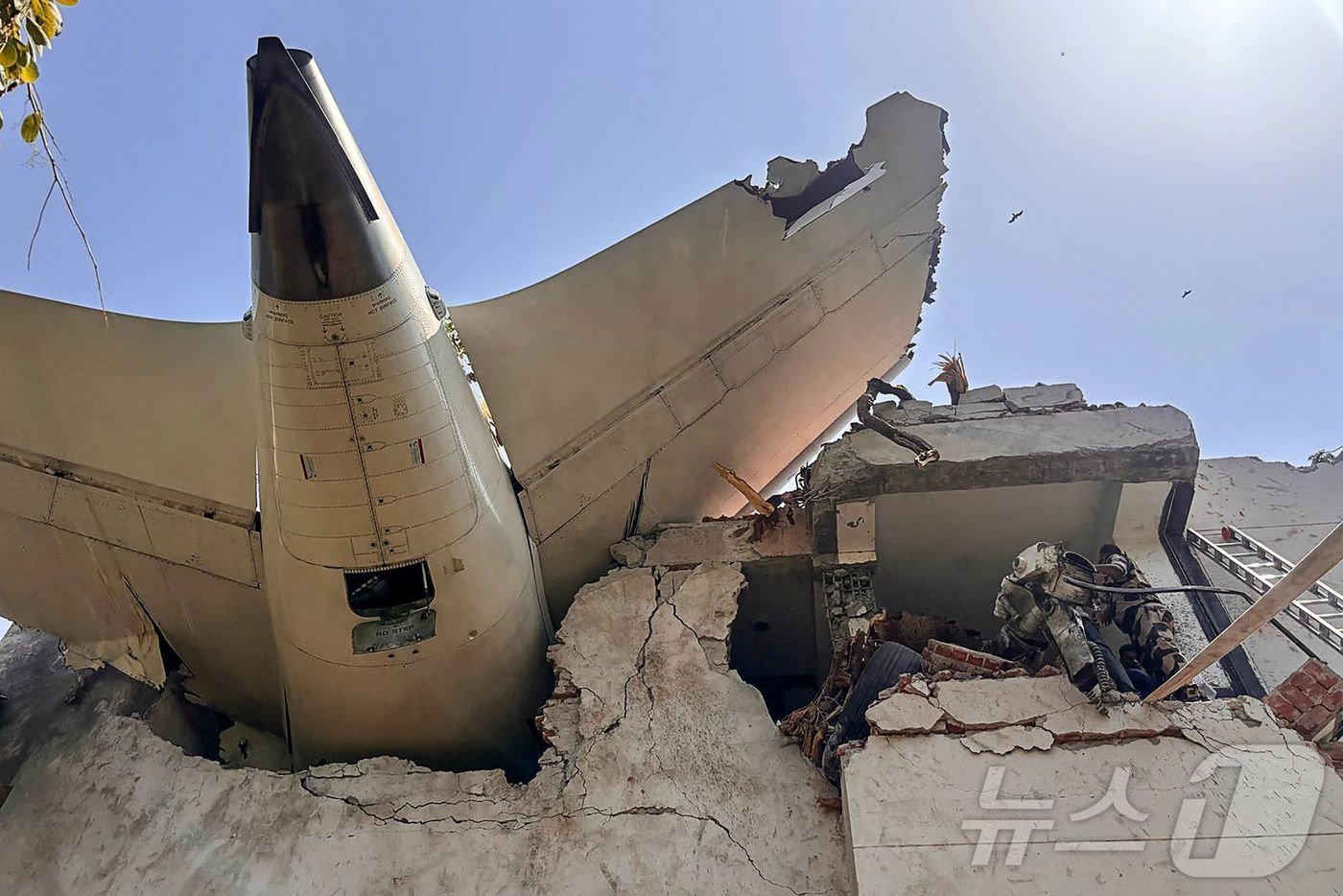 (AFP=뉴스1) = 12일(현지시간) 242명을 태우고 인도 서부 아메다바드 공항 근처에서 추락한 인도 국영항공사 에어인디아 171편 여객기의 꼬리 부분이 건물에 처박혀 있다. …